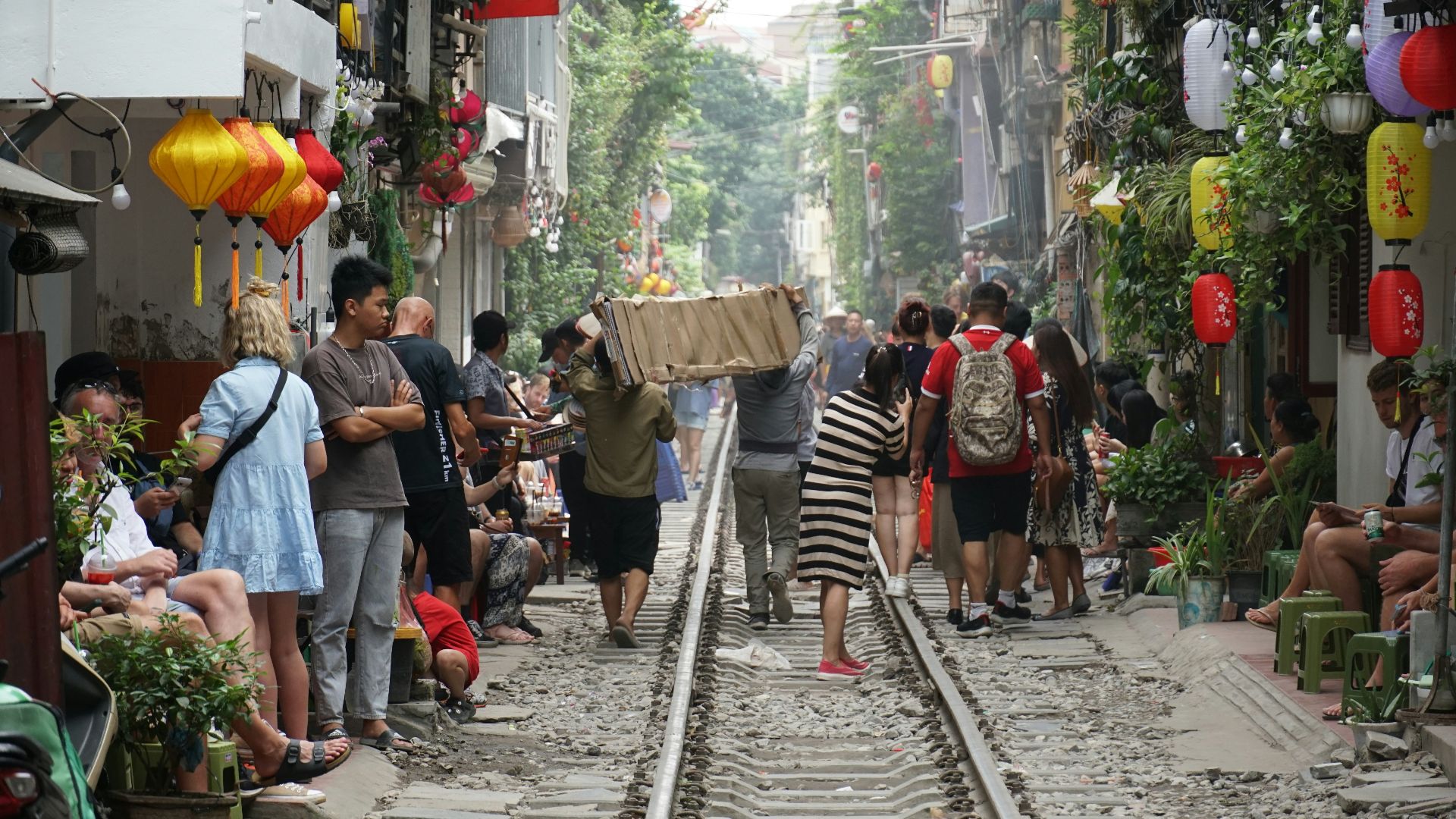 a group of people walking down a street next to a train track