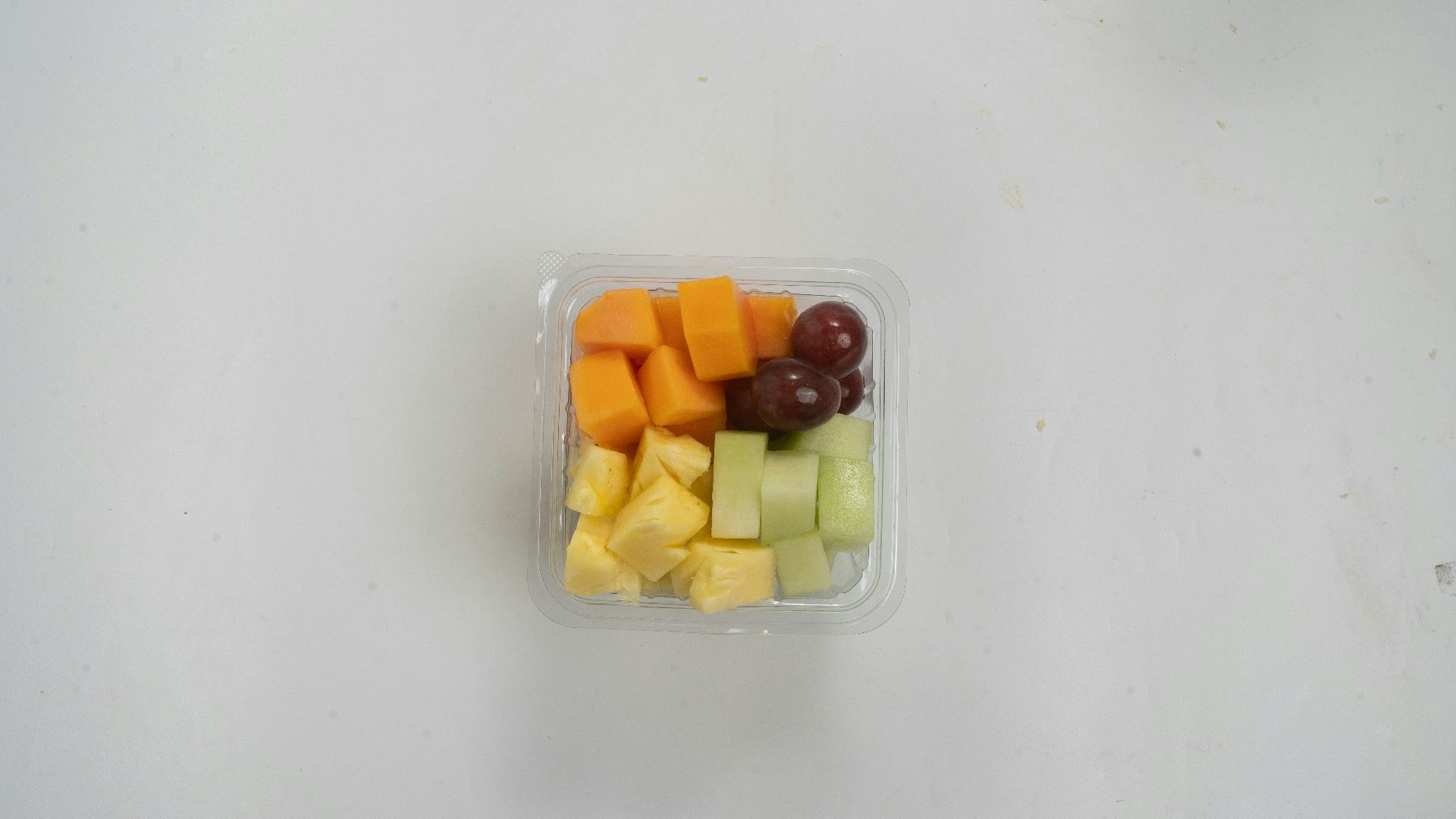 A plastic container filled with cut up fruit