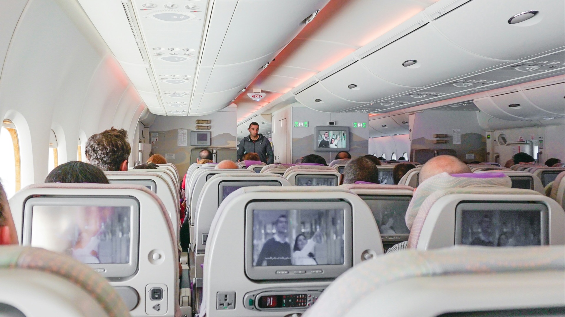 man walking down the aisle of airplane