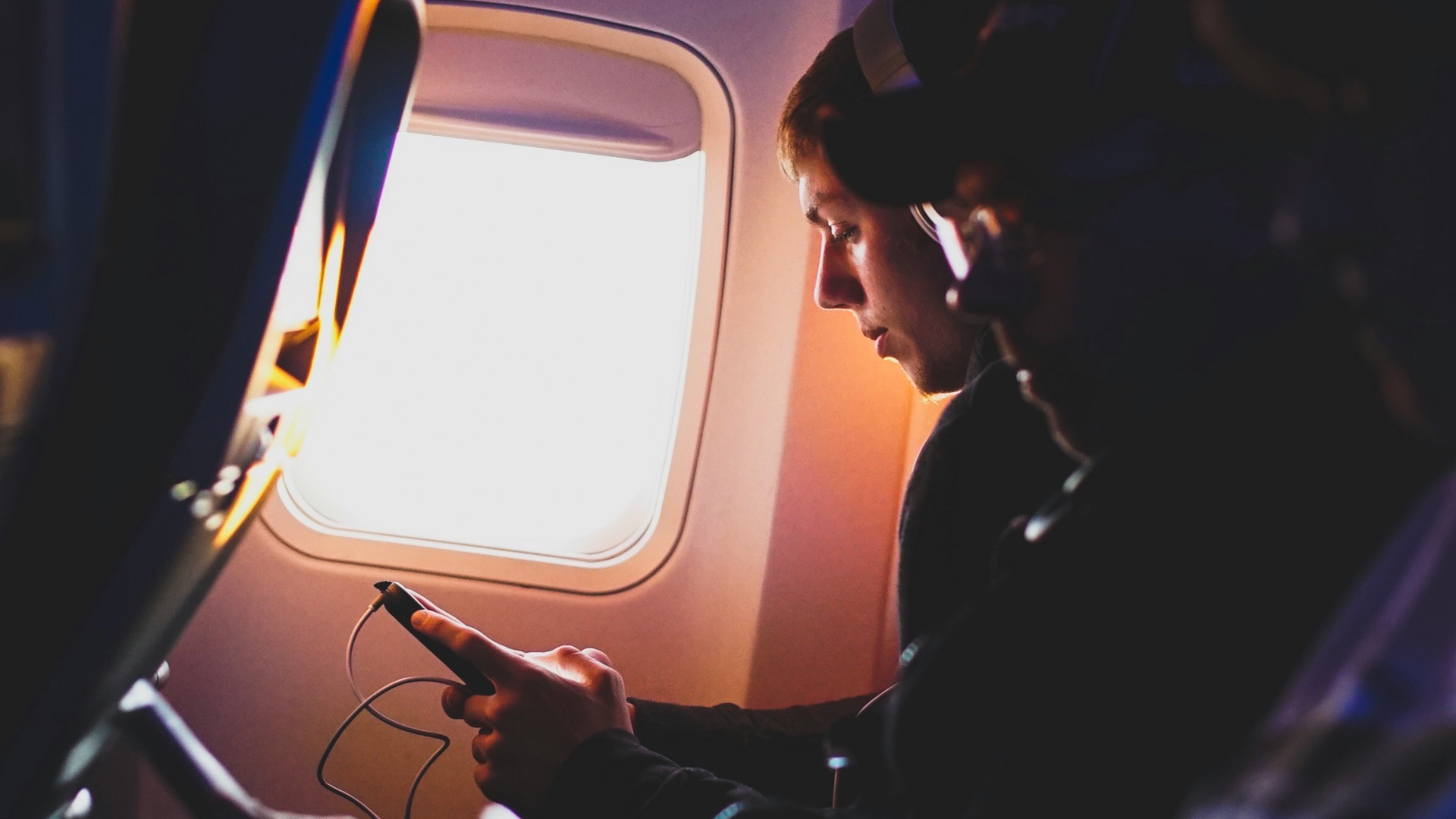 photo of three people listening to music inside airplane