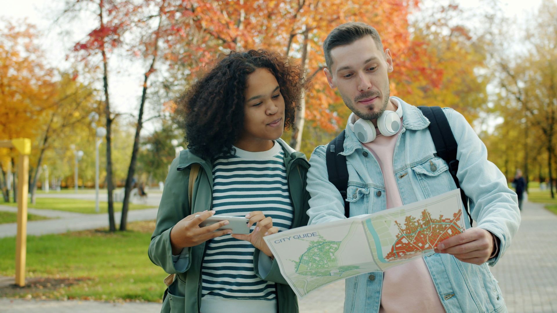 Couple looking at map in park during autumn