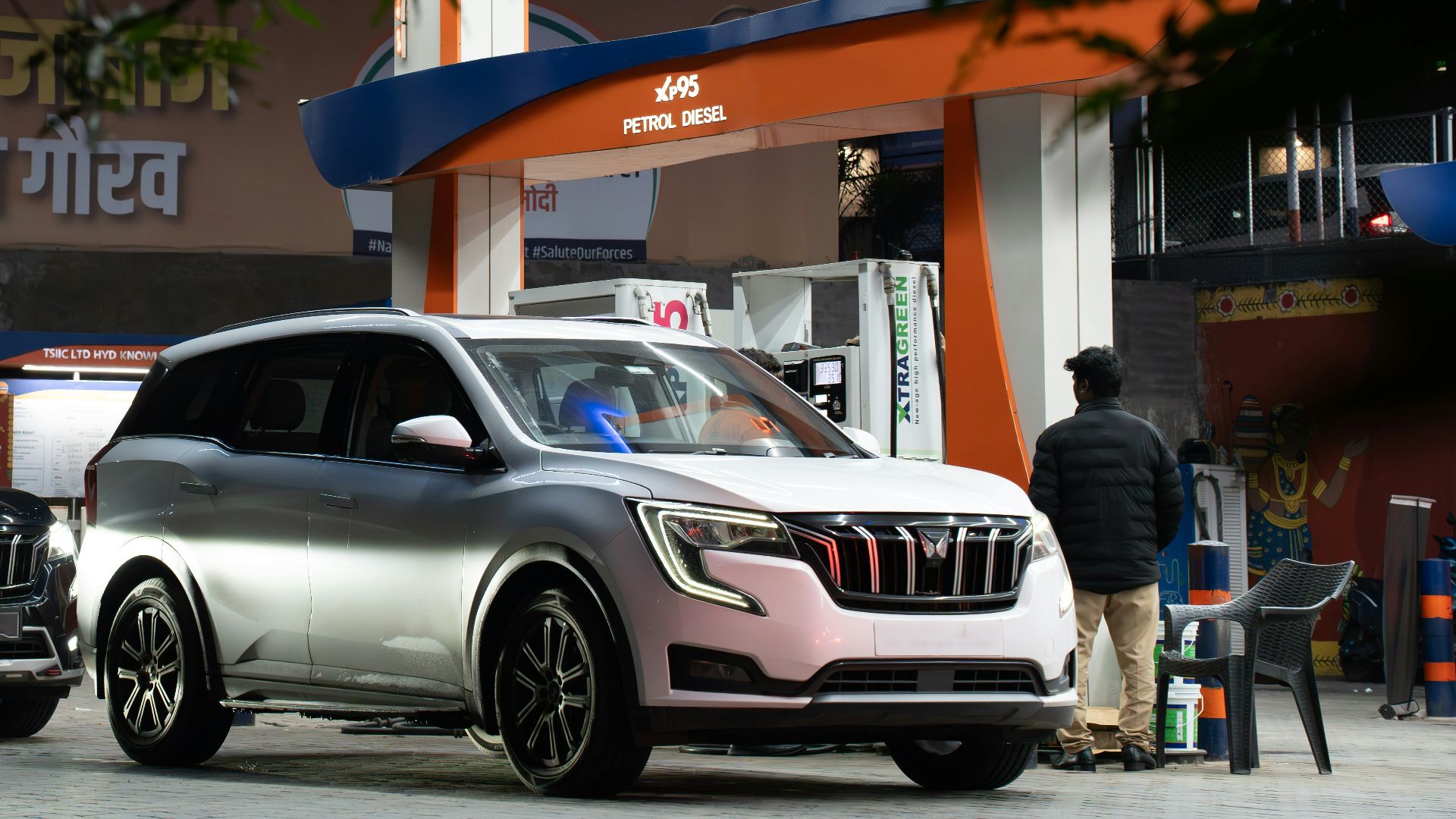 Cars at a brightly lit gas station at night.