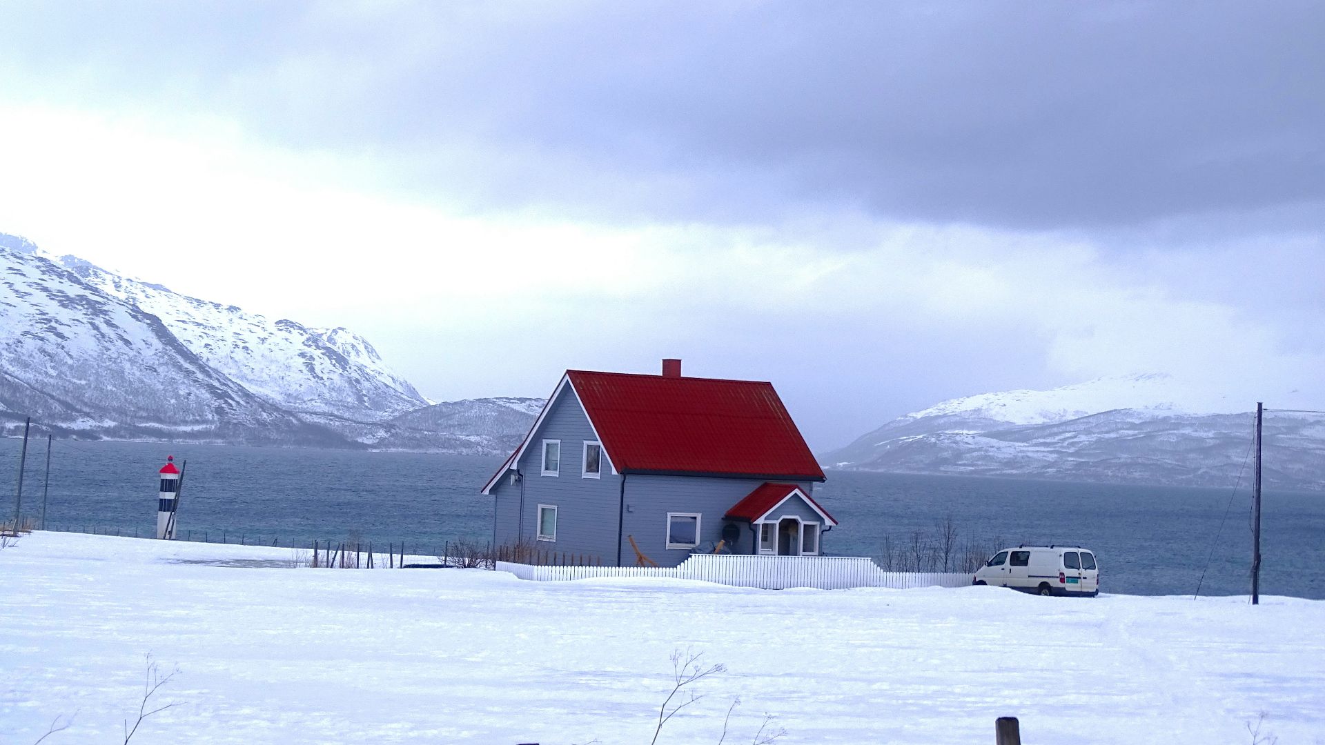 gray and red house near body of water and mountains