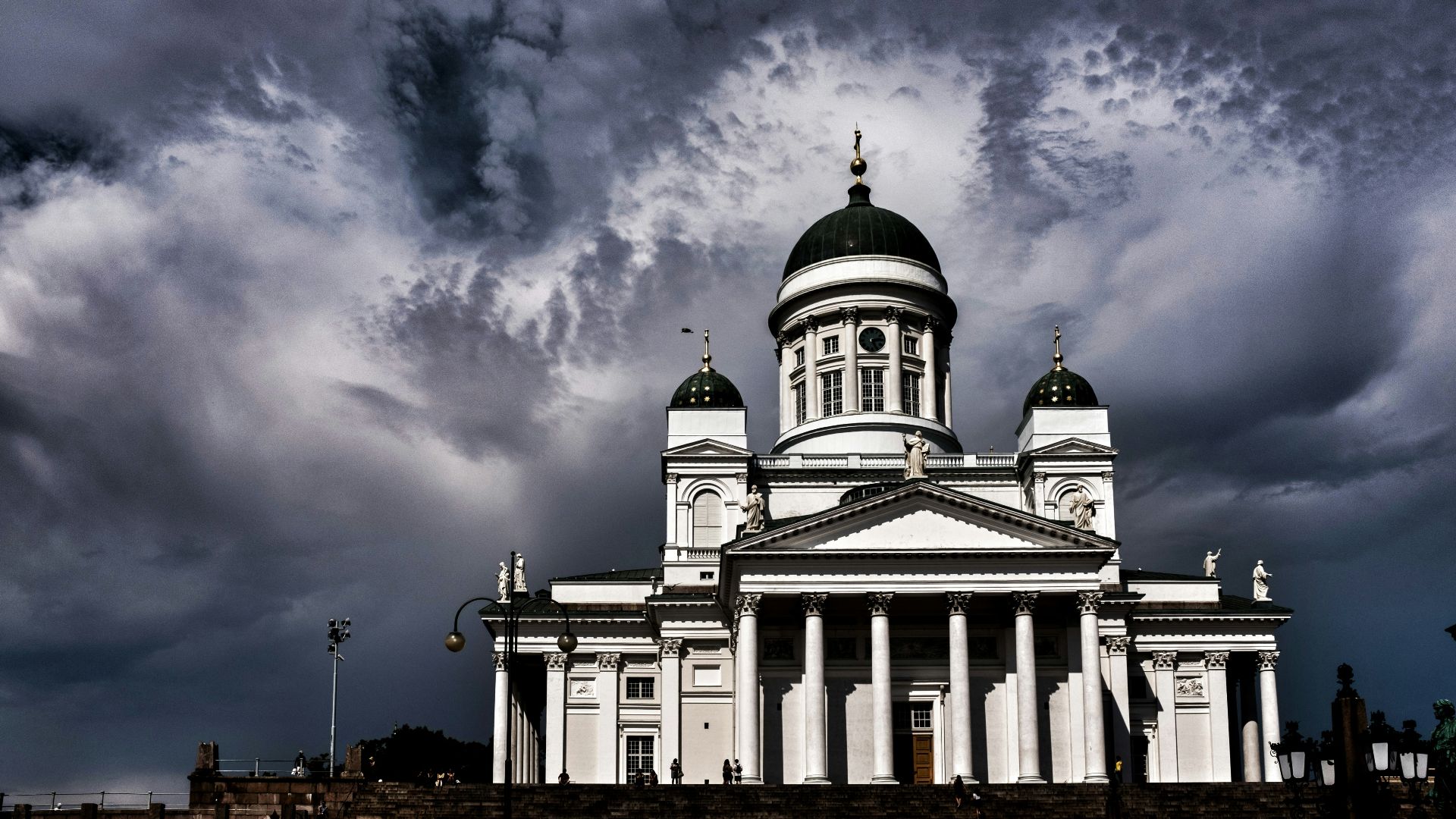 Helsinki cathedral stands majestic under a stormy sky.
