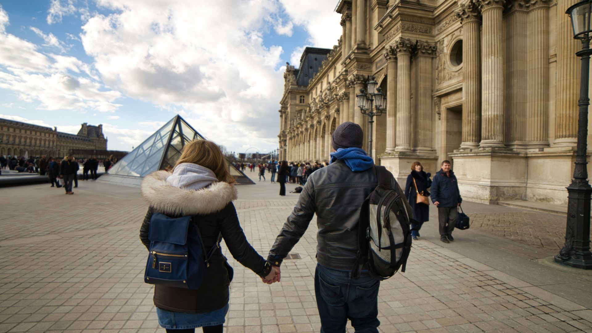 man and woman holding hands while walking on gray concrete ground during daytime