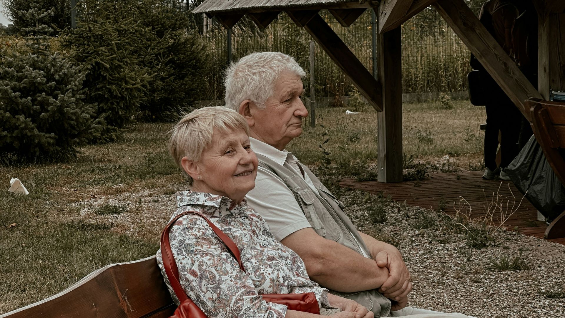 a man and a woman sitting on a wooden bench