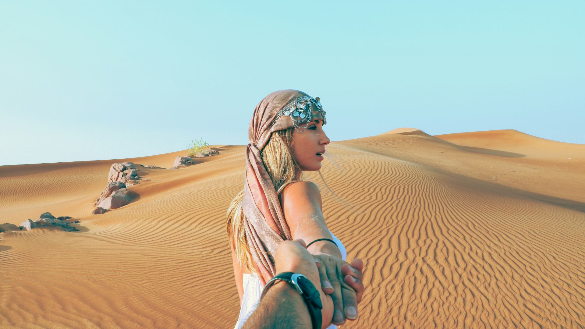 man and woman holding hands while in desert