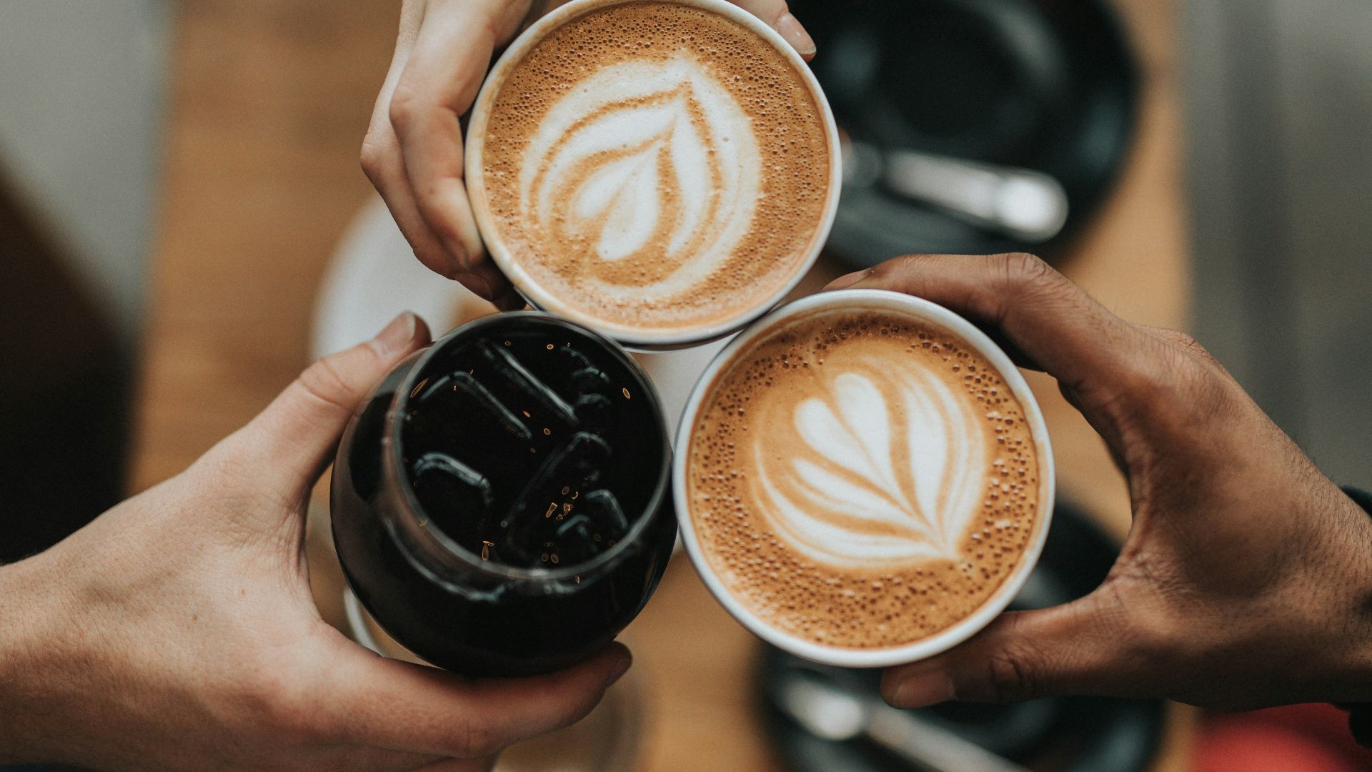 three person holding beverage cups