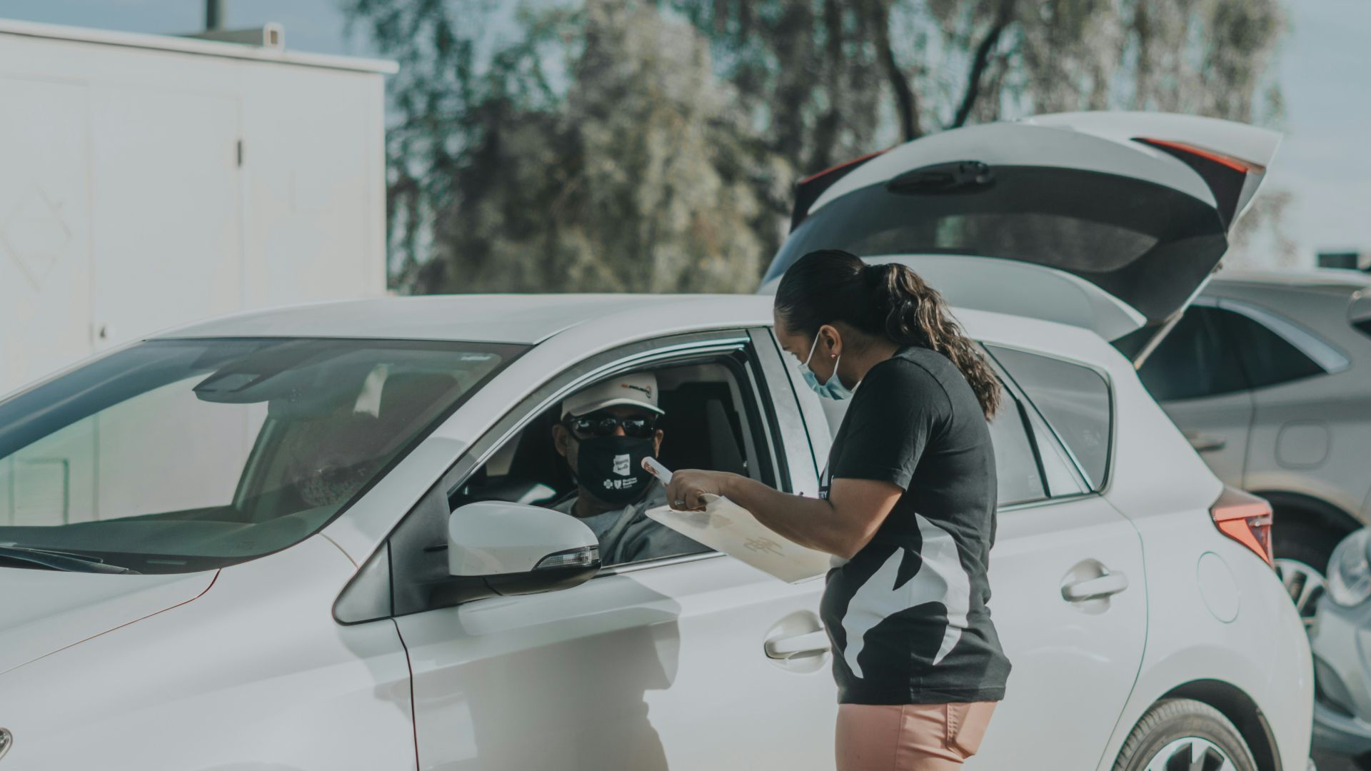 woman in black and white shirt and orange shorts leaning on white car during daytime
