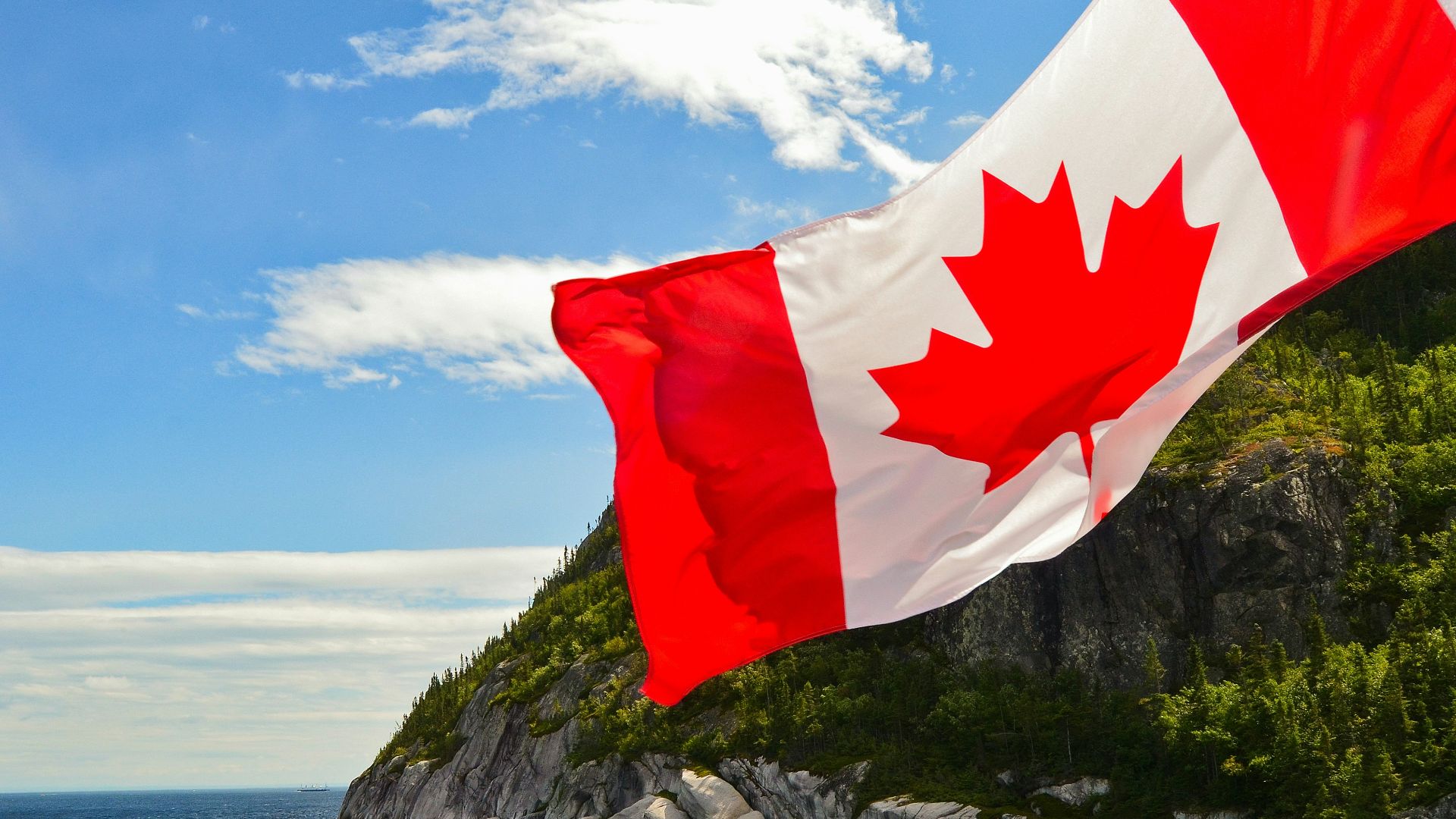 red and white flag on rock formation near body of water during daytime