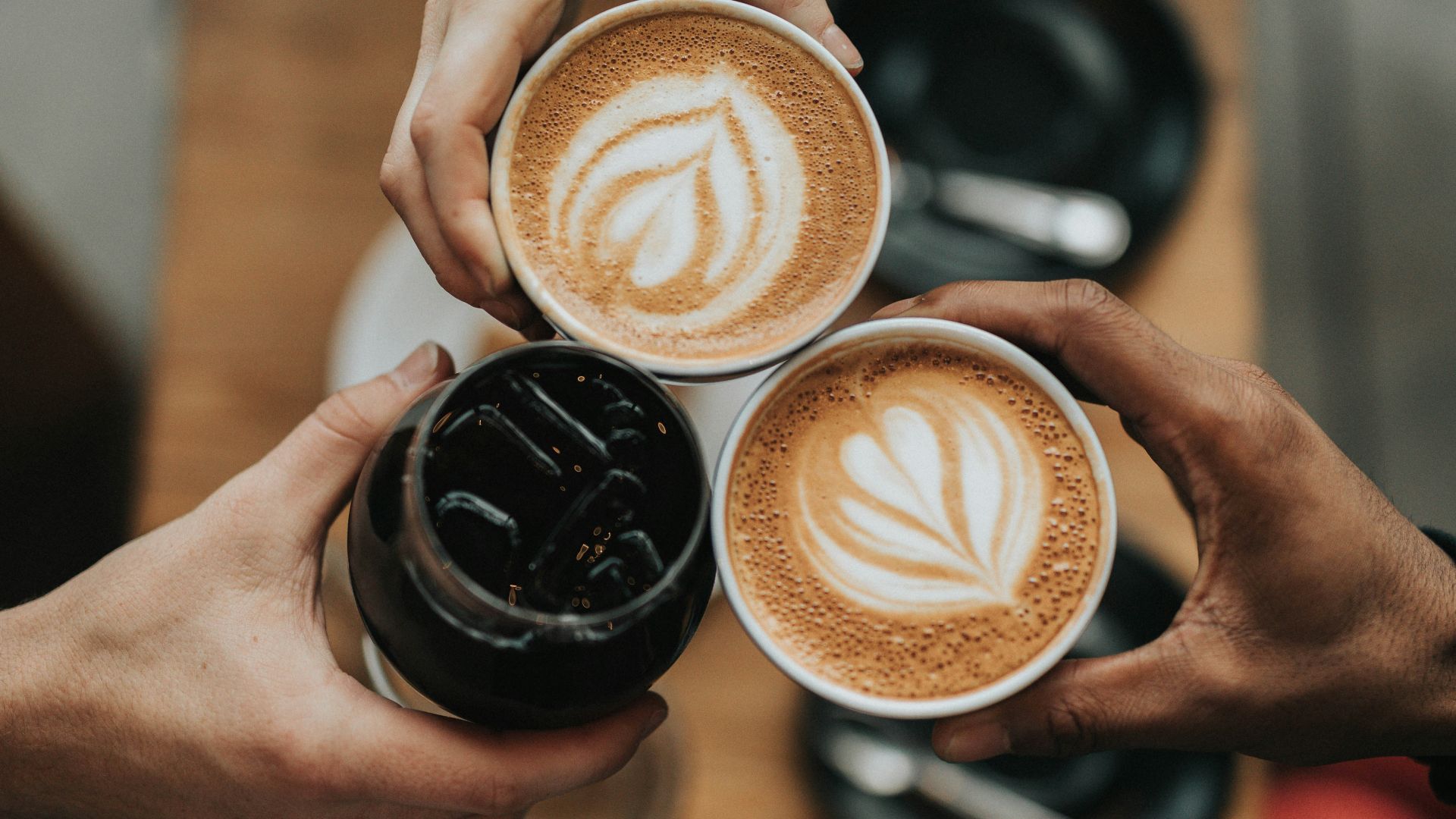 three person holding beverage cups