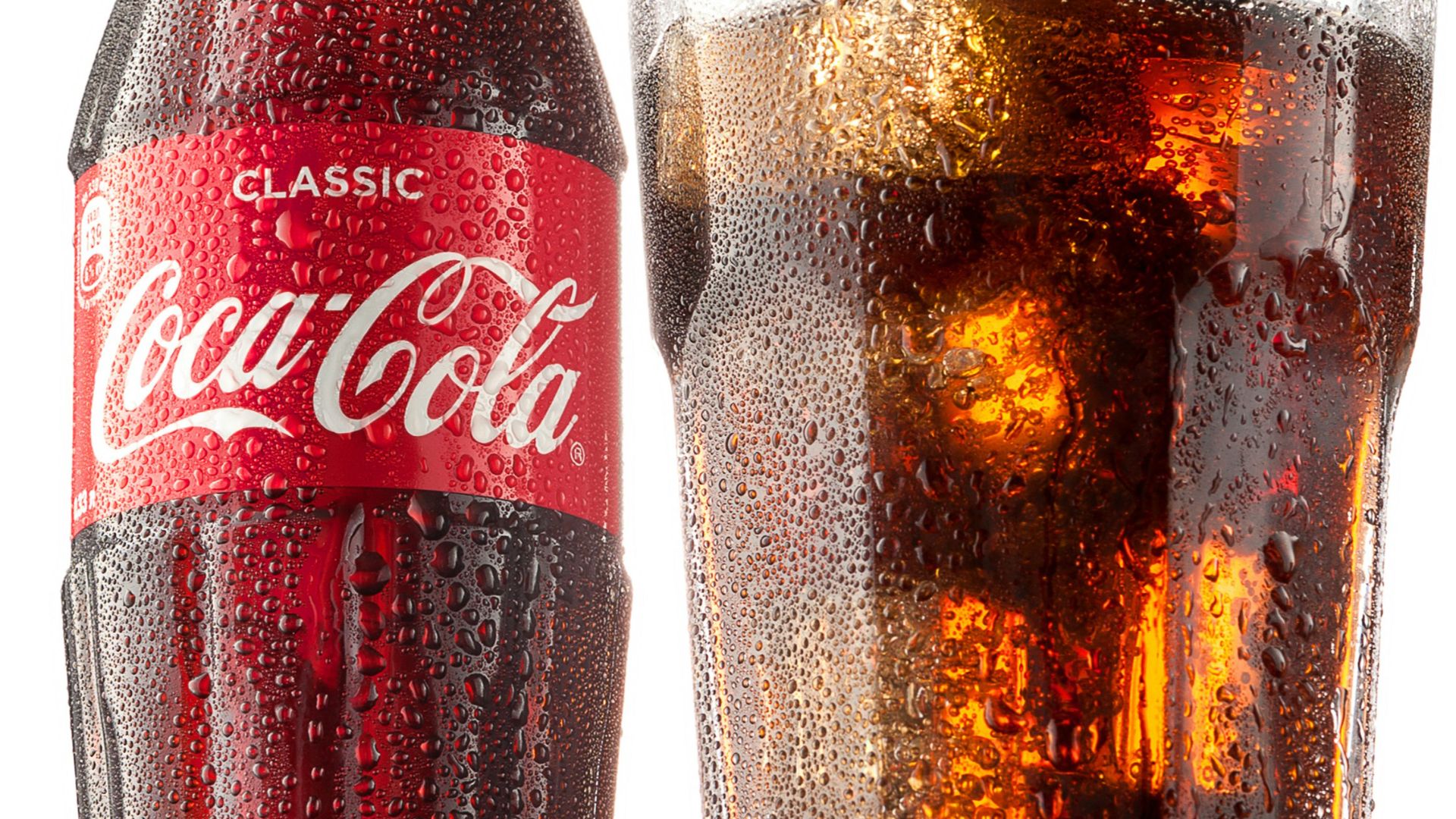 coca cola bottle beside drinking glass