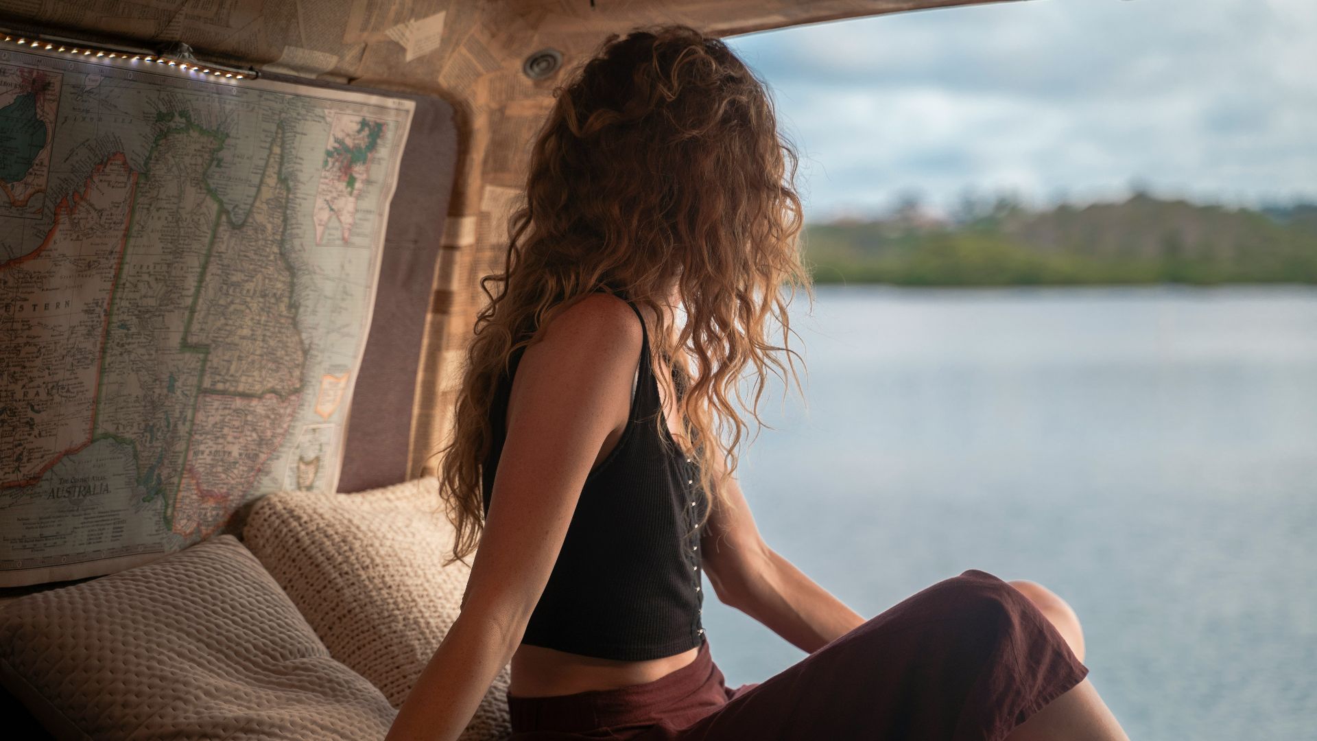 woman wearing black spaghetti strap top sitting viewing body of water