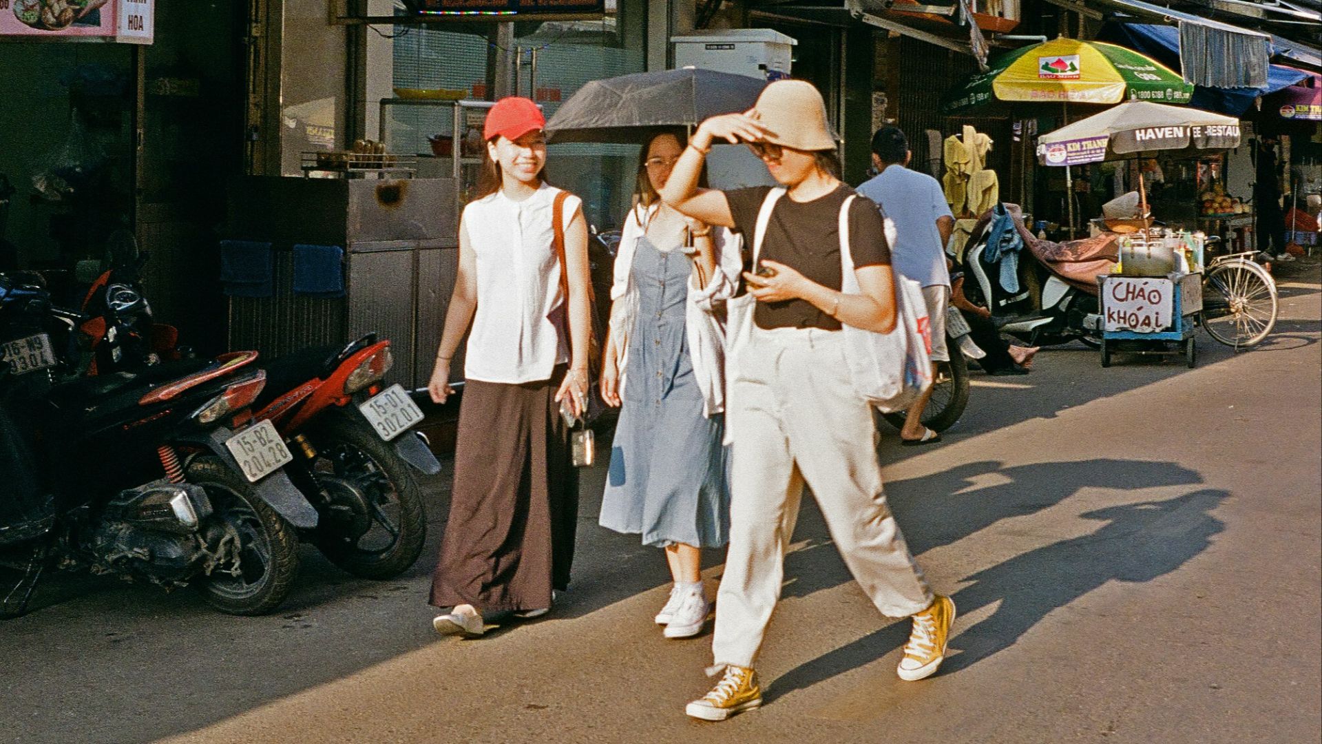A group of people walking down a street next to tall buildings