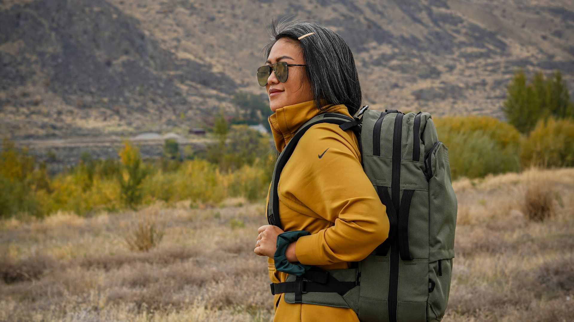 woman in black and white plaid skirt with black backpack standing on green grass field during