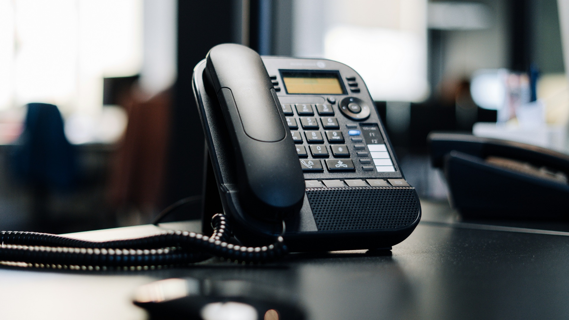 black ip desk phone on black wooden table