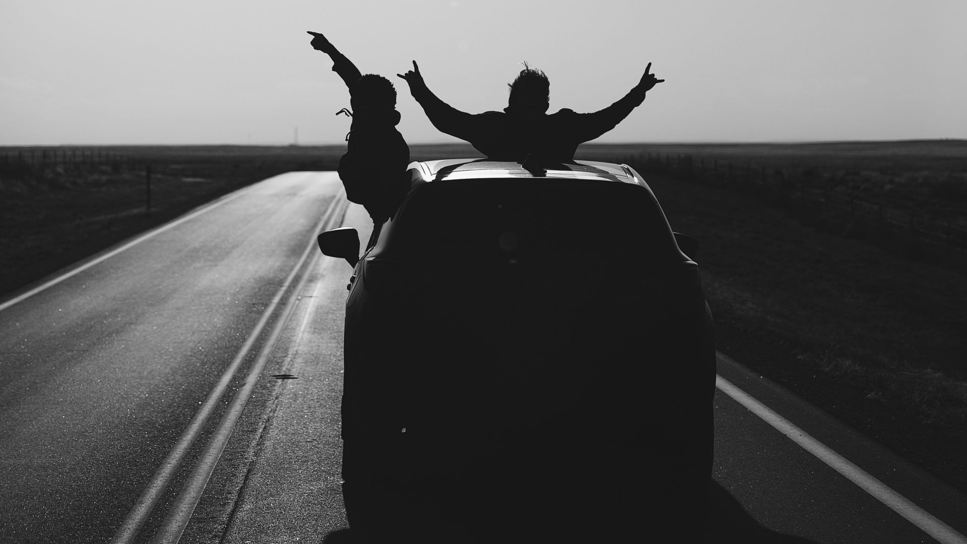 grayscale photo of man riding on motorcycle on road