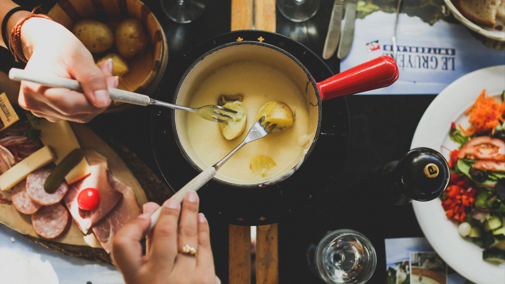 two person holding fork dipping food on sauce