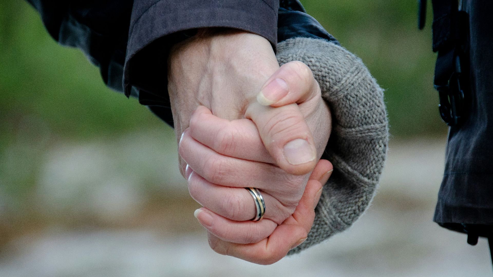 person in blue jacket holding womans hand