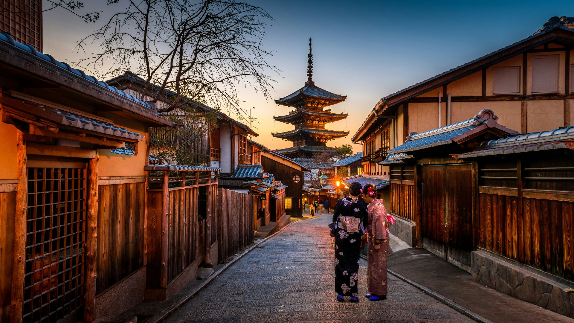 two women in purple and pink kimono standing on street