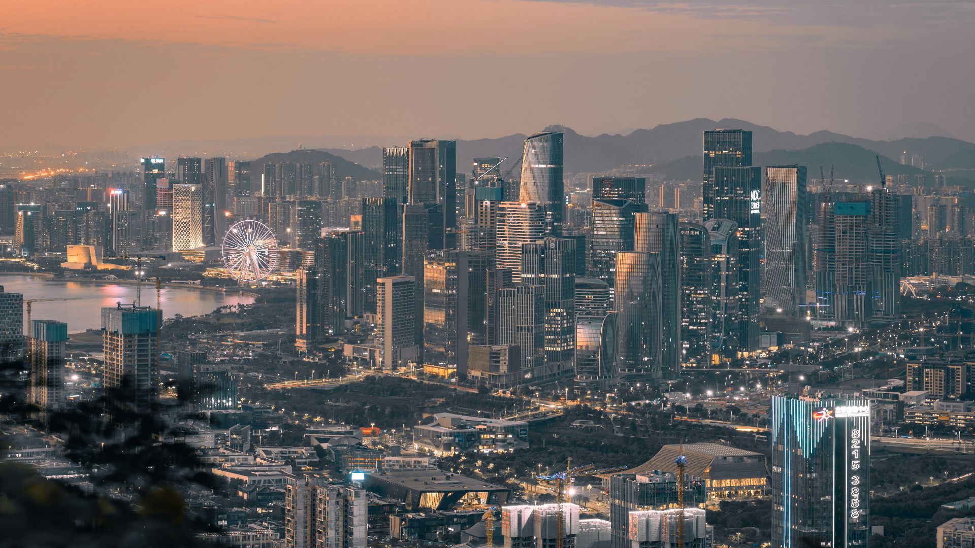 a view of a city at night with a ferris wheel in the distance