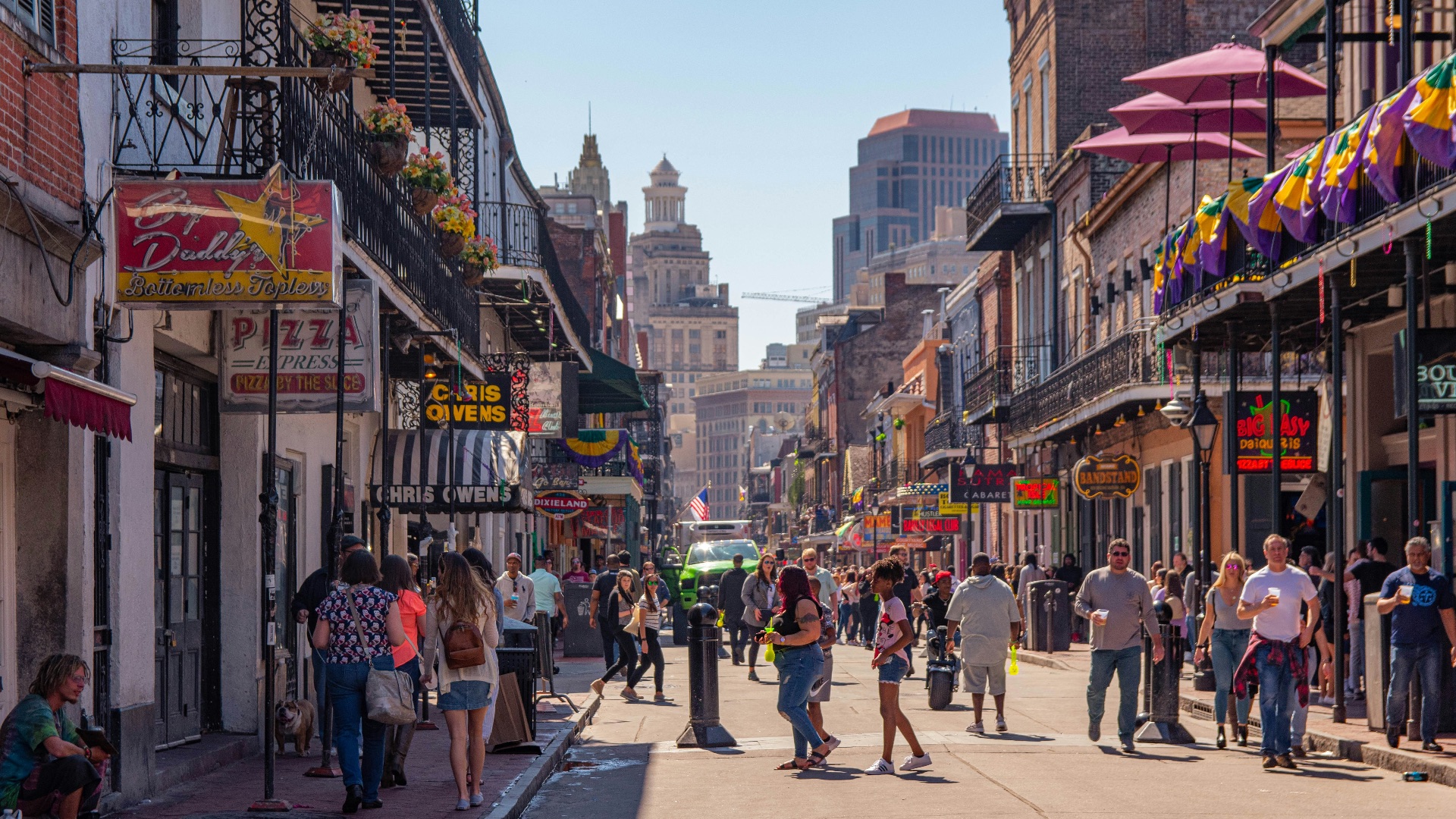 a group of people walking down a street next to tall buildings
