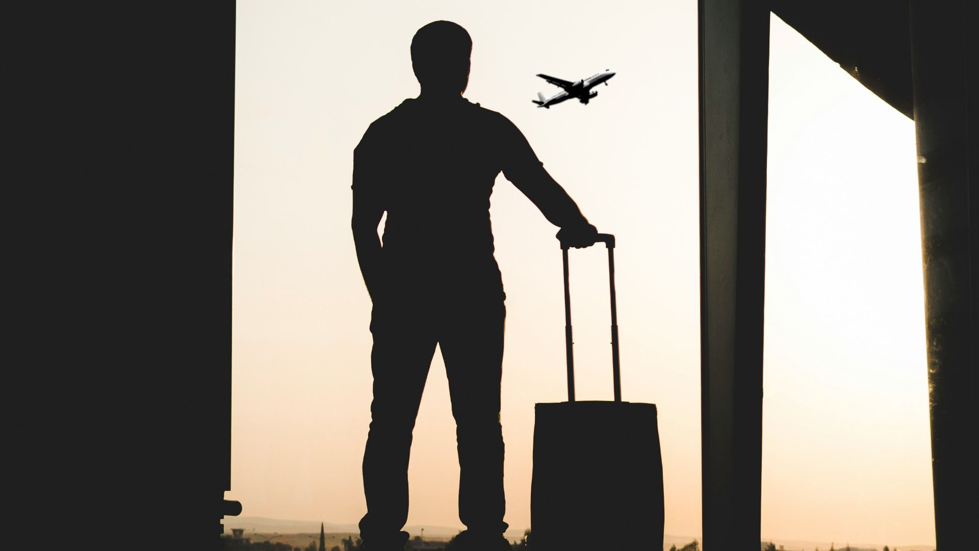 silhouette of man holding luggage inside airport
