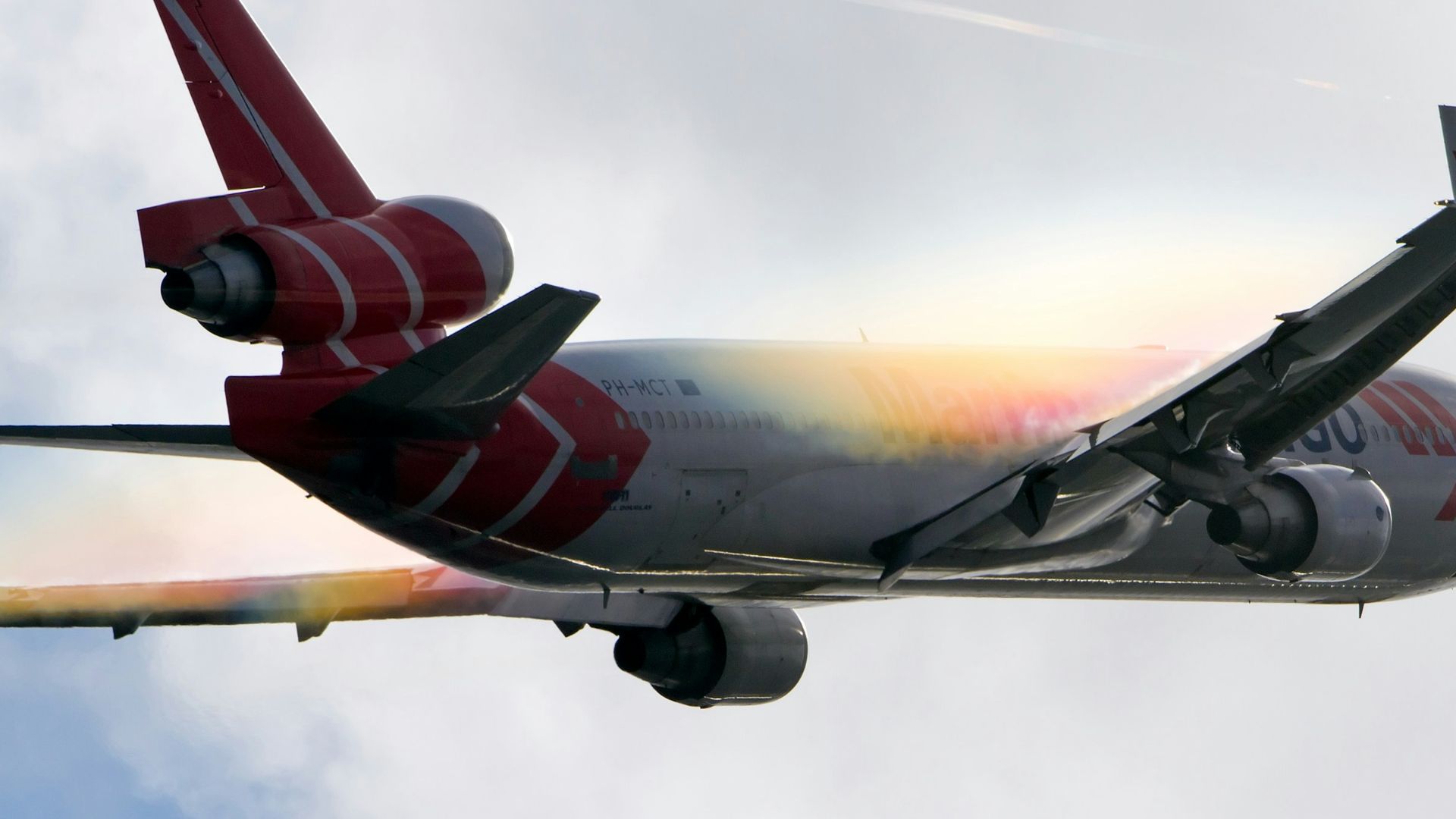 white and red airplane under white clouds during daytime