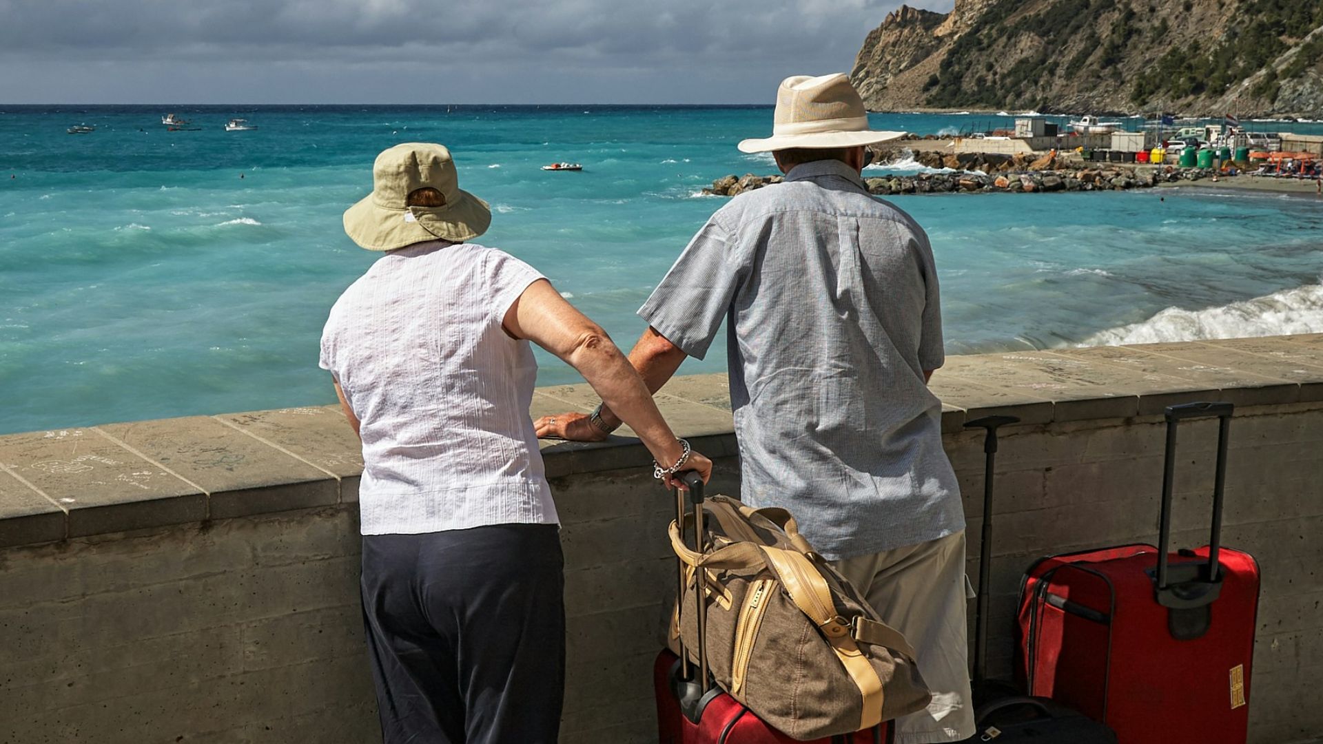 man and woman standing beside concrete seawall looking at beach
