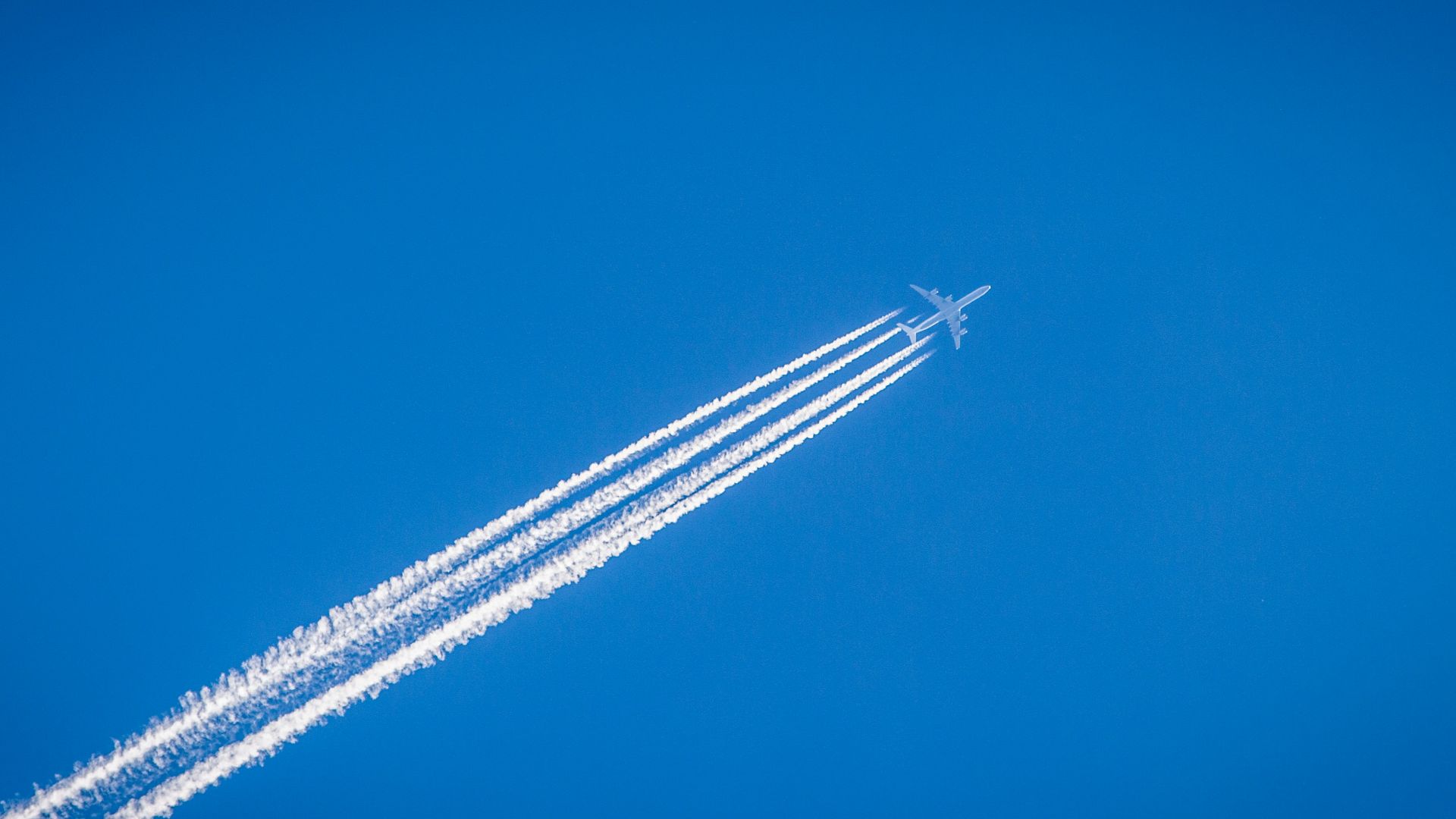 white airplane flying under the blue sky
