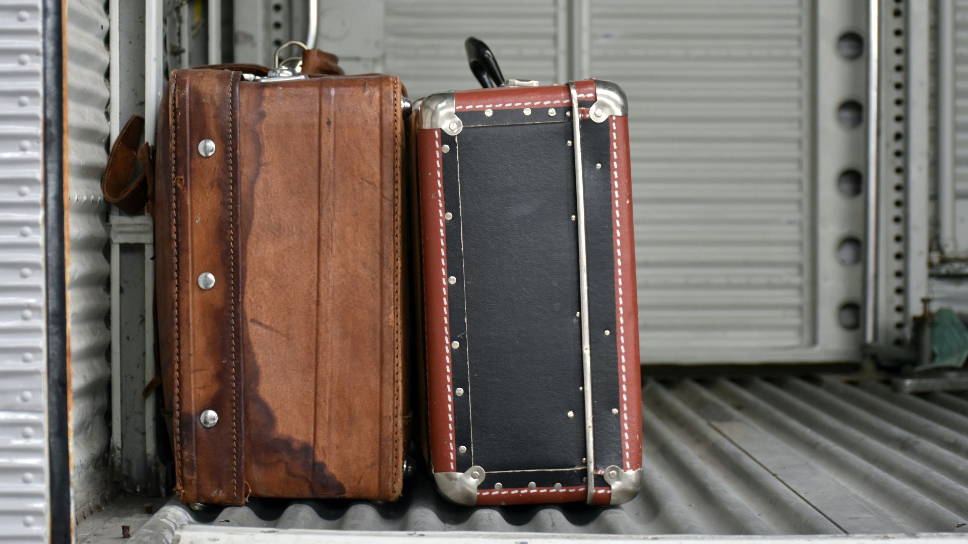 Two vintage suitcases on a ribbed surface.