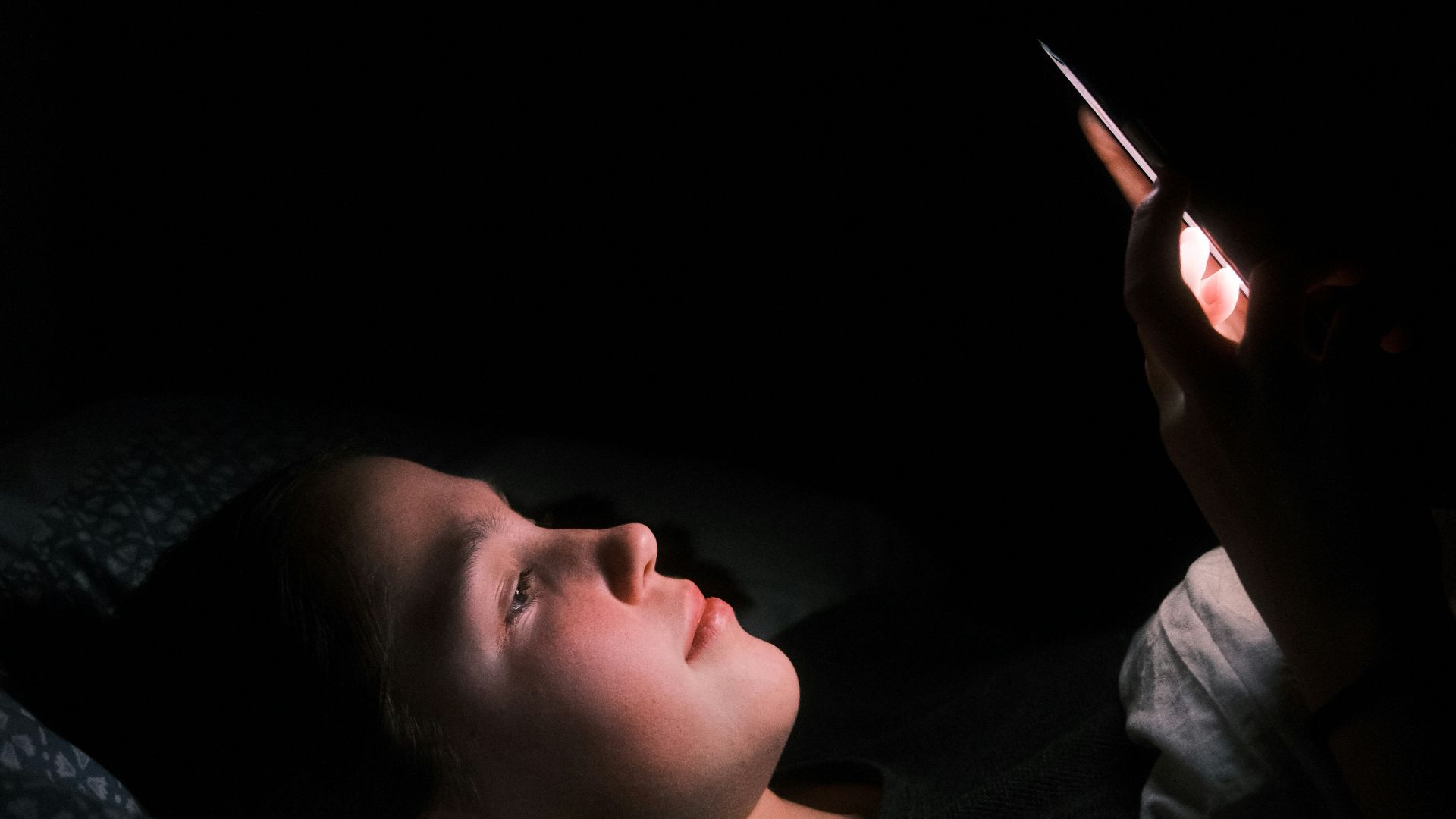 a woman laying in bed with a light on her face