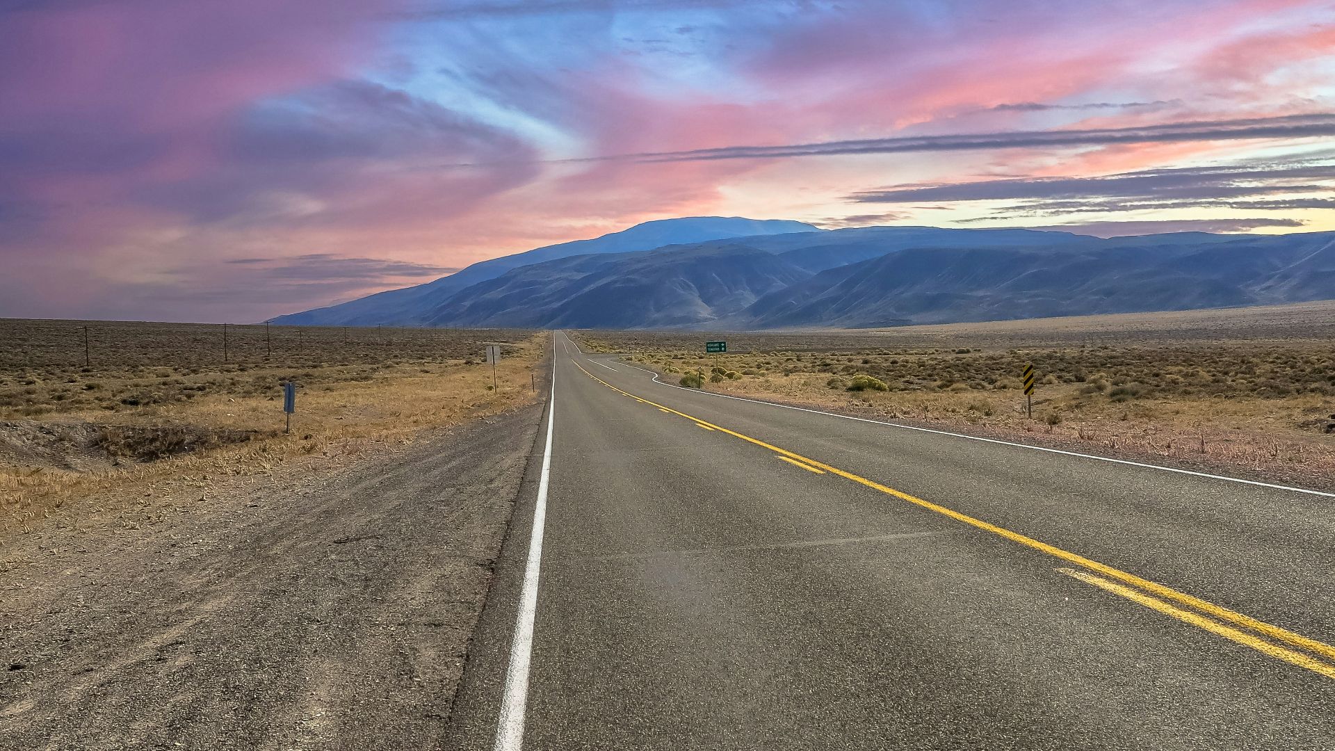 a long empty road with mountains in the background
