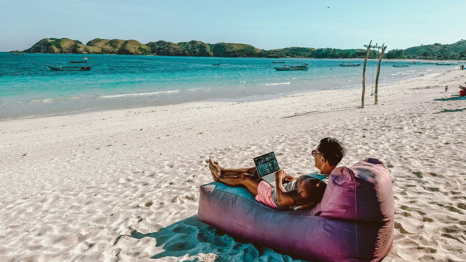 a man sitting on a bean bag on the beach