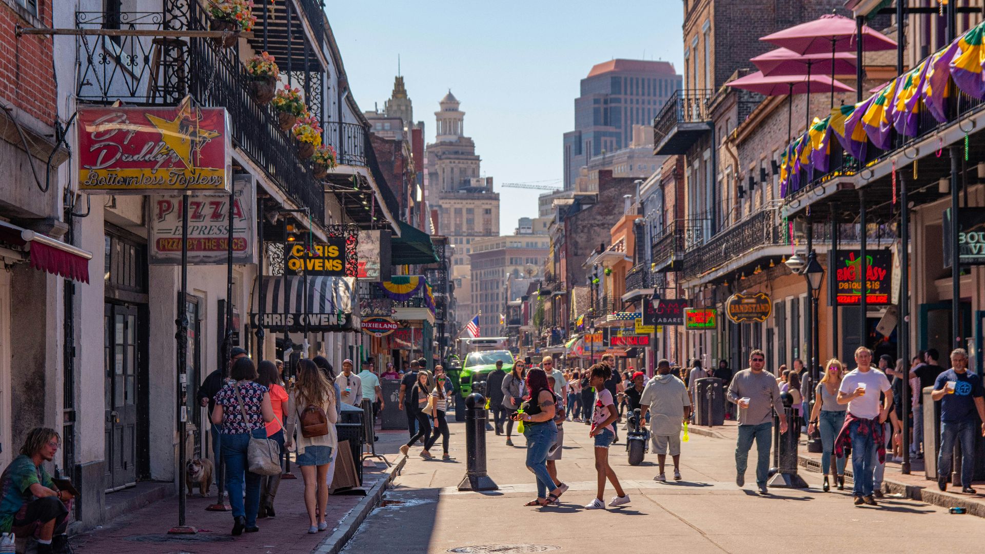 a group of people walking down a street next to tall buildings