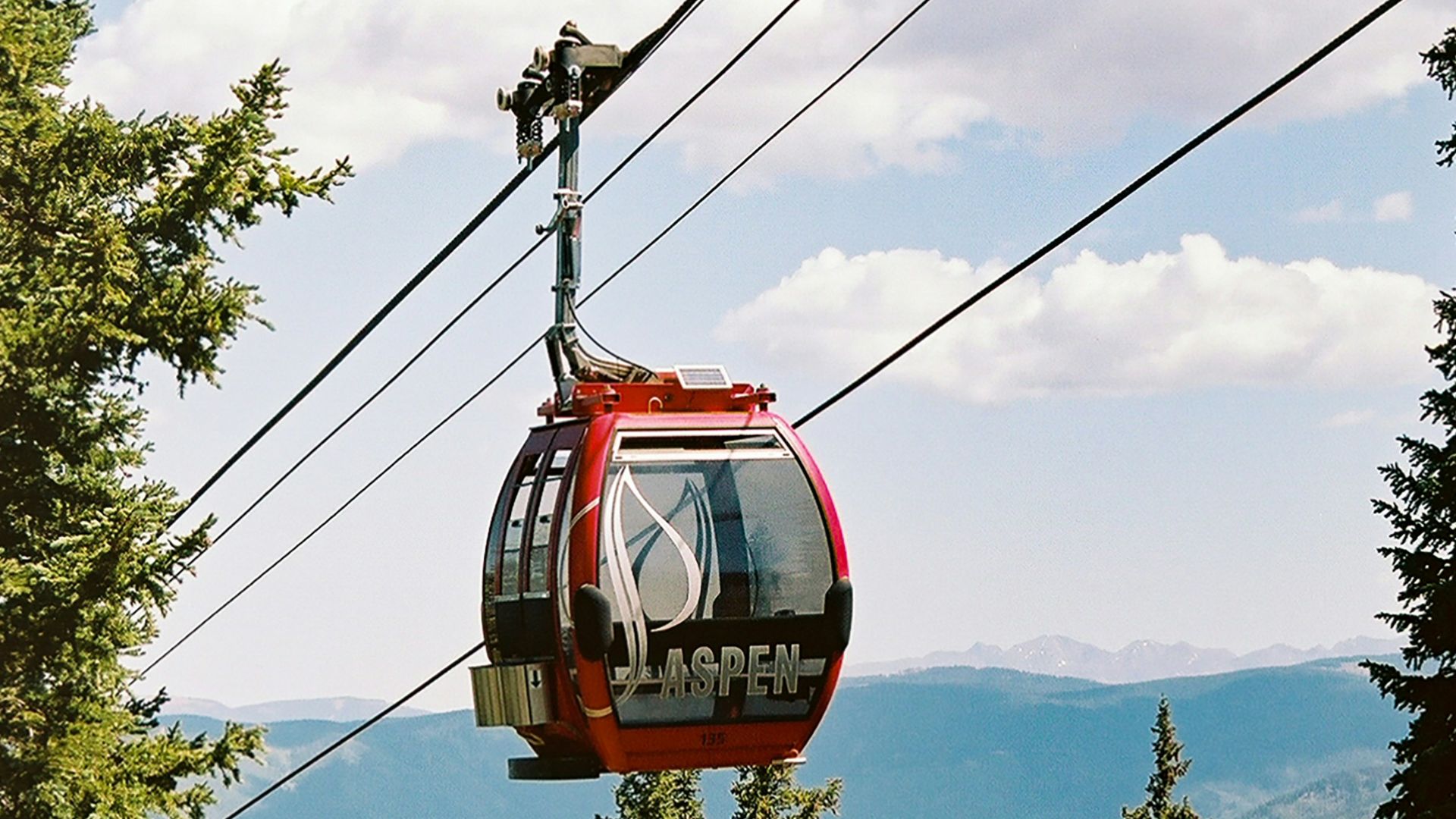 red cable car over green trees during daytime