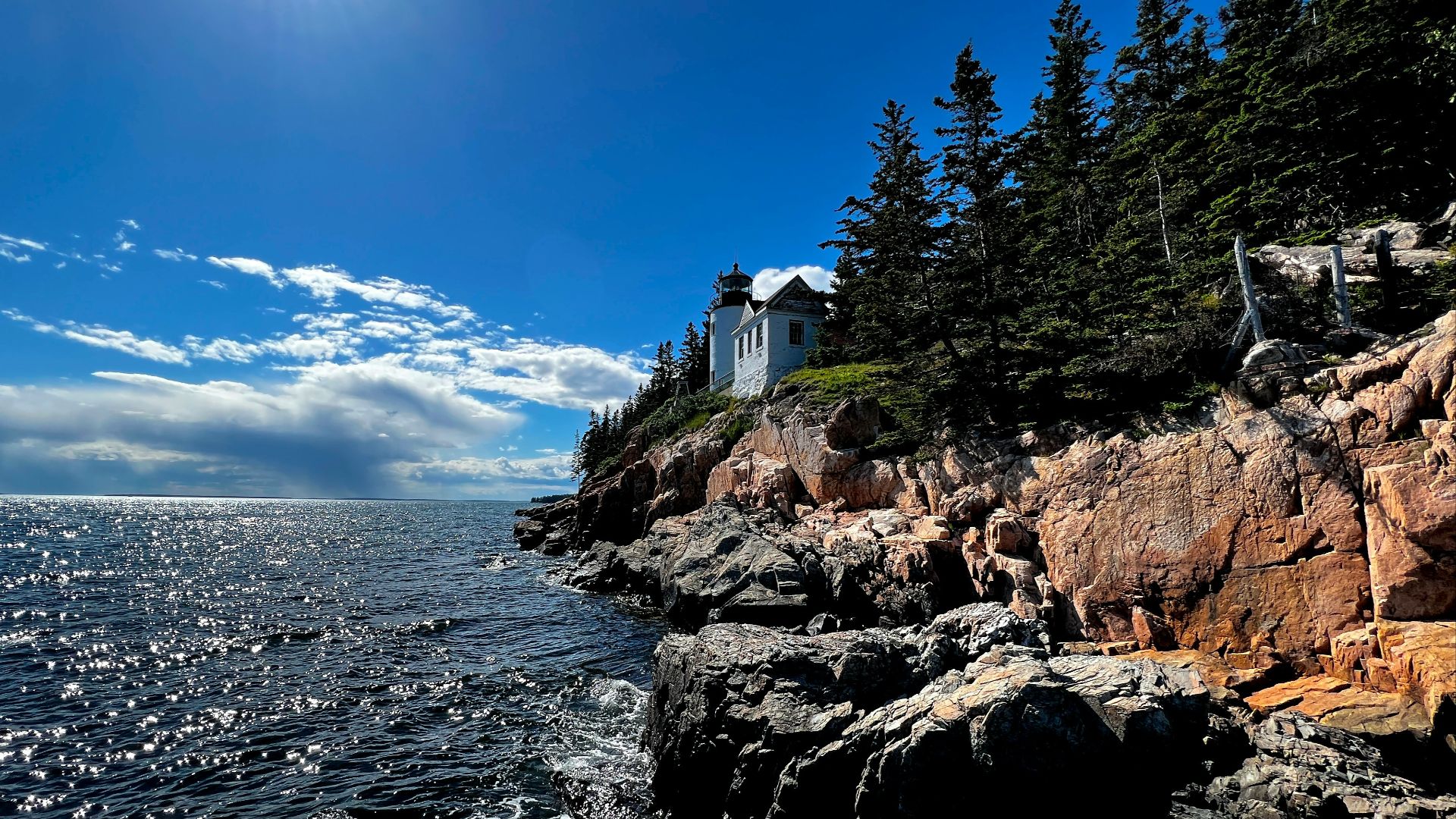 a rocky beach with a house on it with Acadia National Park in the background