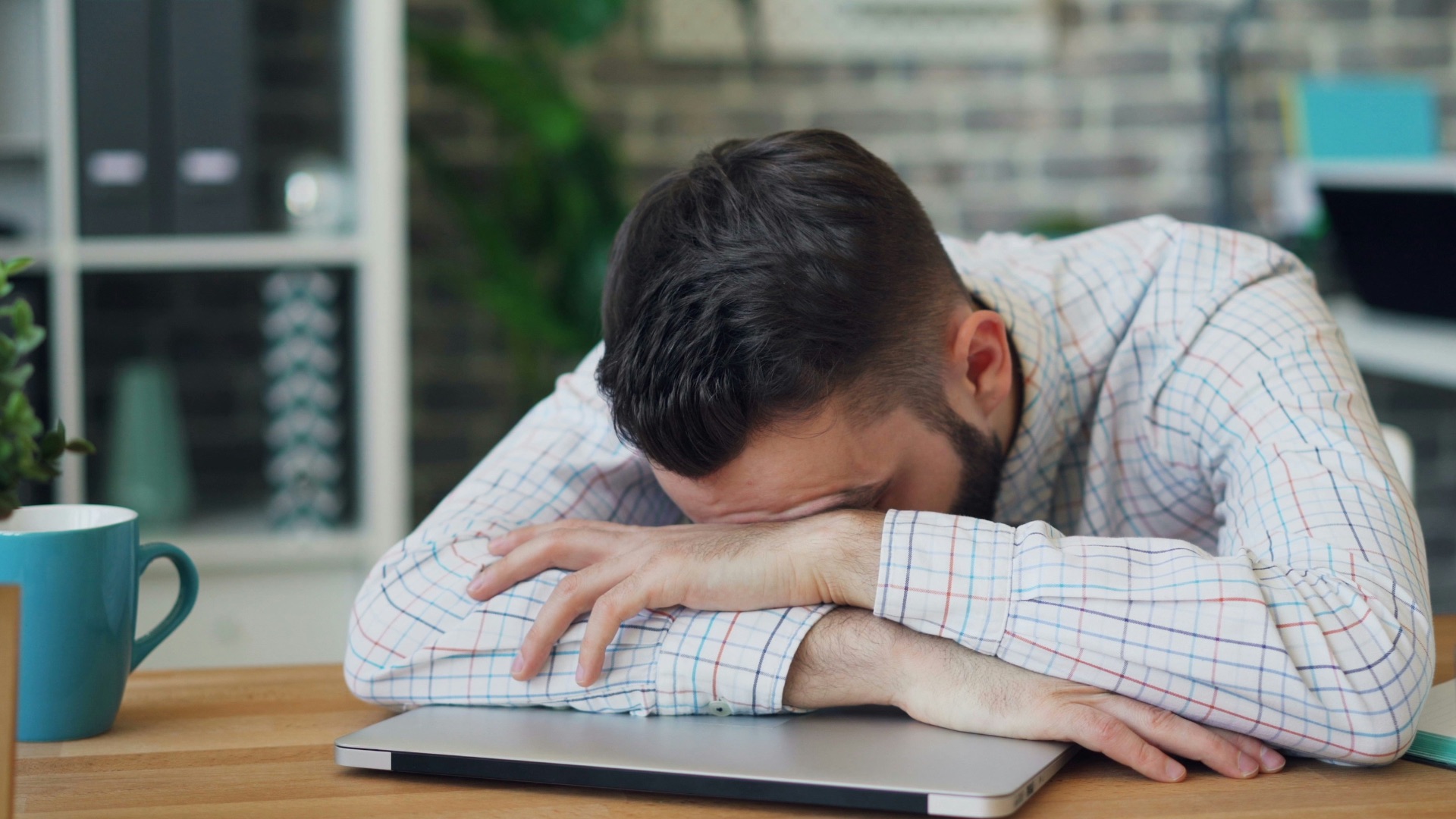 a man sitting at a desk with his head in his hands