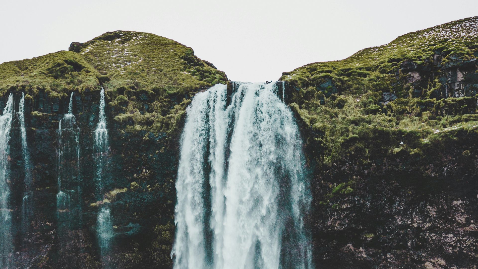 group of people standing near waterfalls