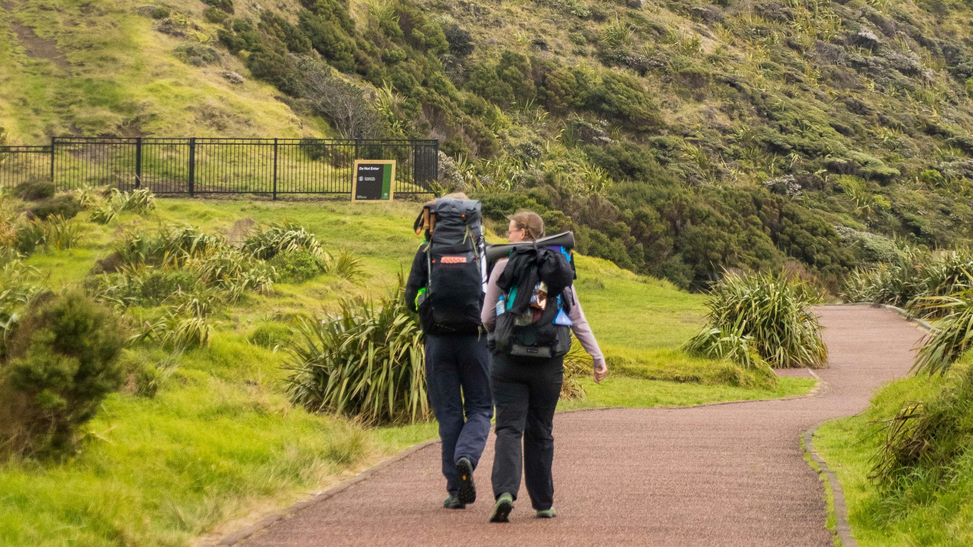 A couple of people walking down a dirt road