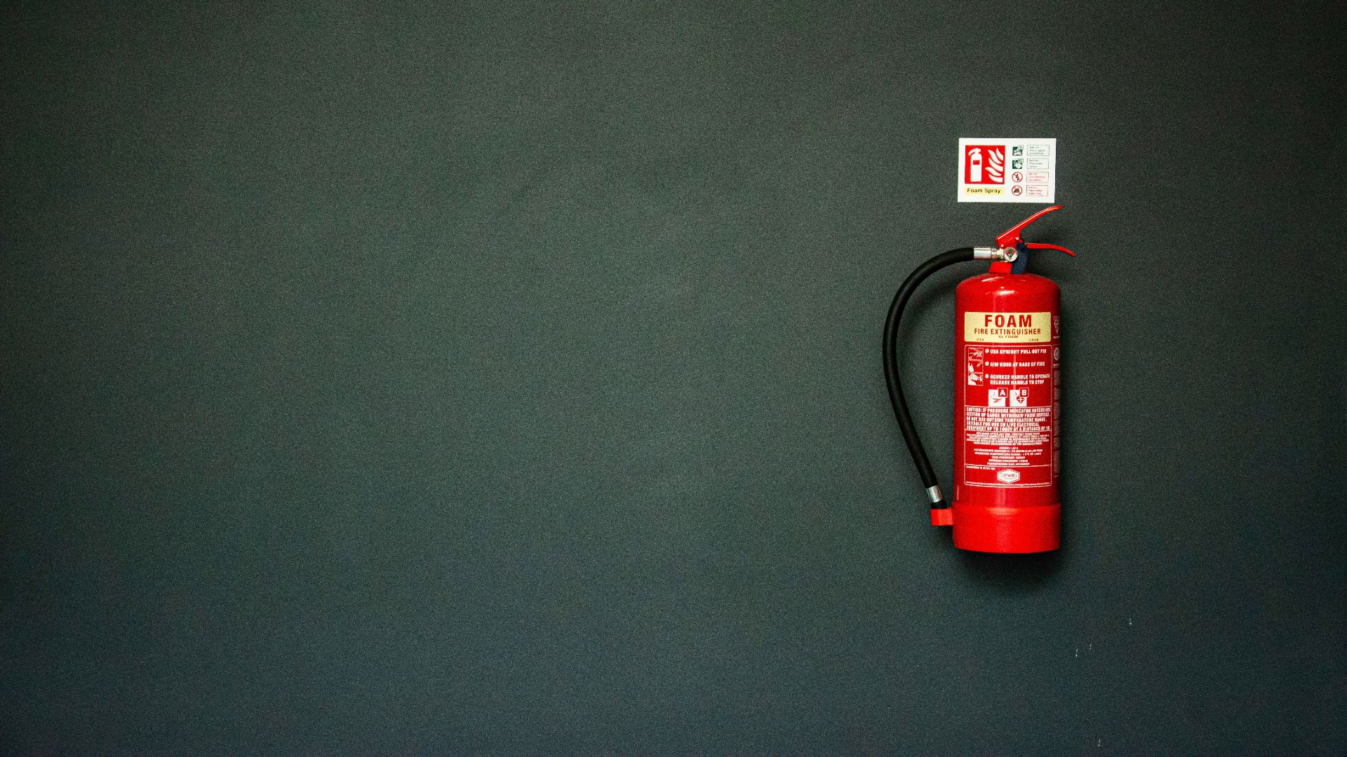 red fire extinguisher on gray wall
