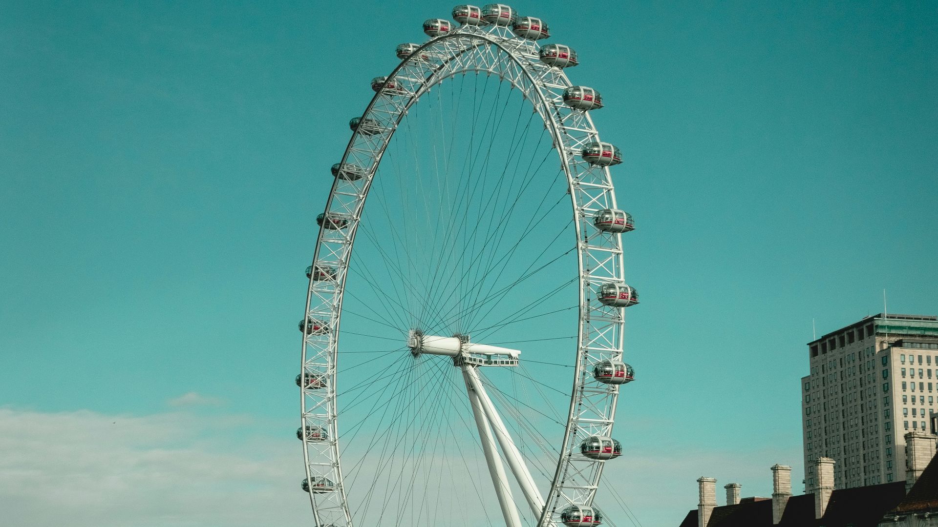 a ferris wheel by water with London Eye in the background