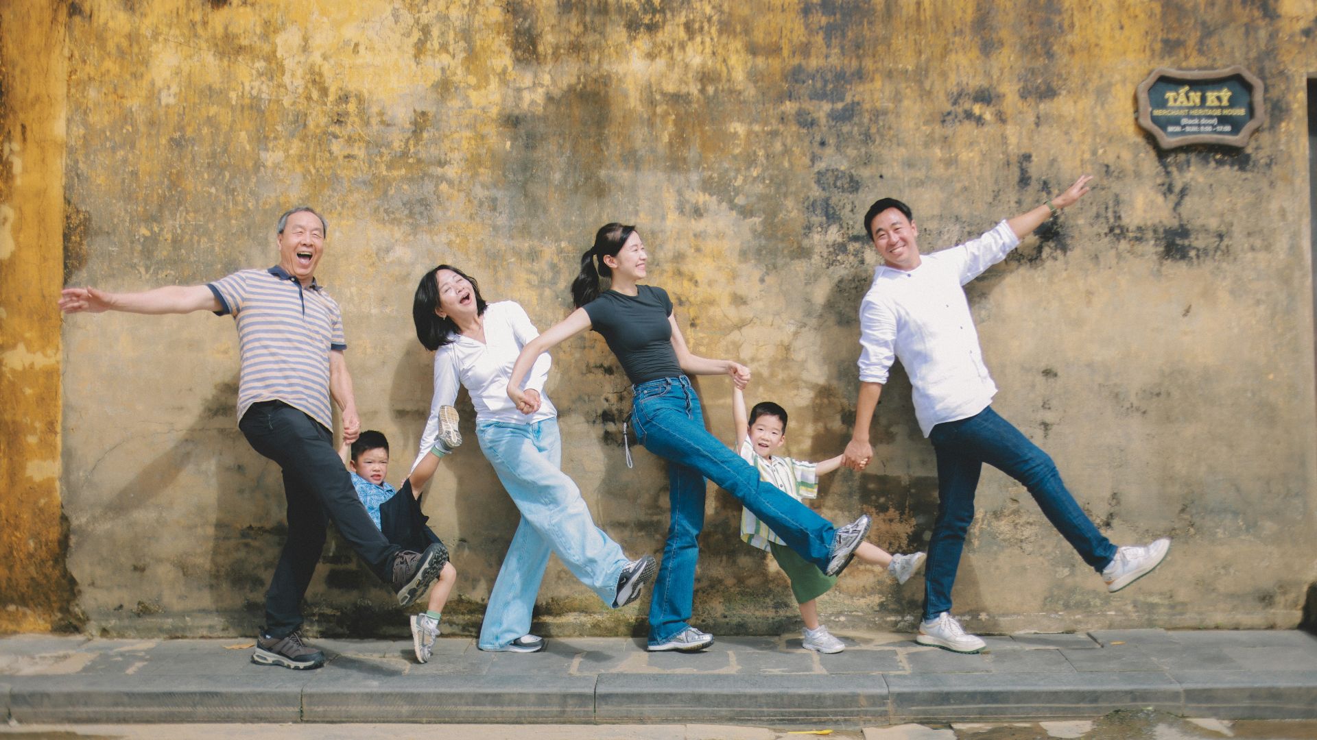 Family posing playfully against a textured wall.