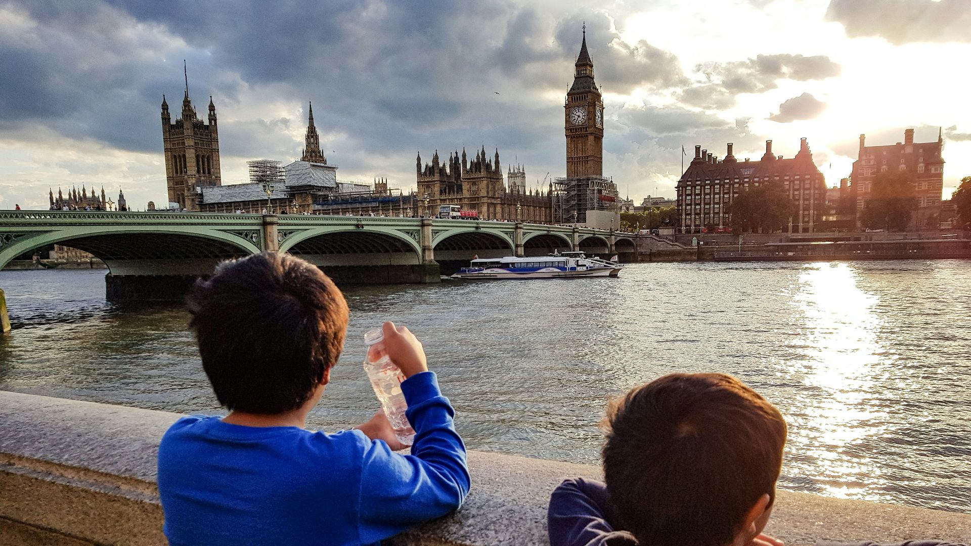 two boys watching golden hour near bridge