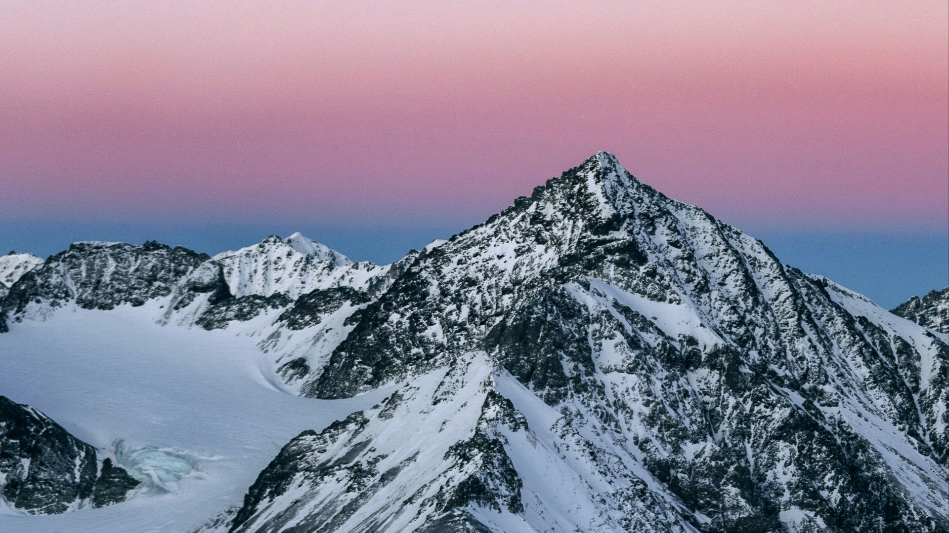 a snowy mountain with a pink sky