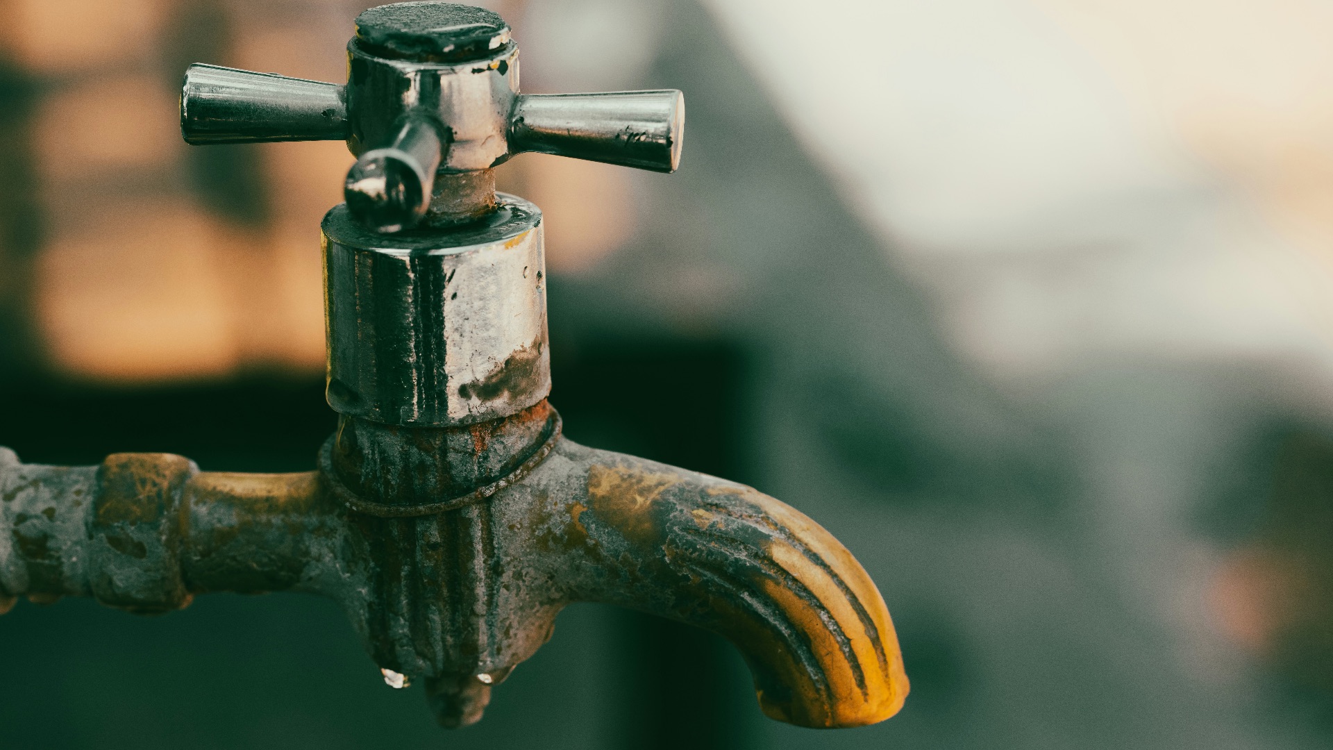 a close up of a metal faucet with water dripping from it