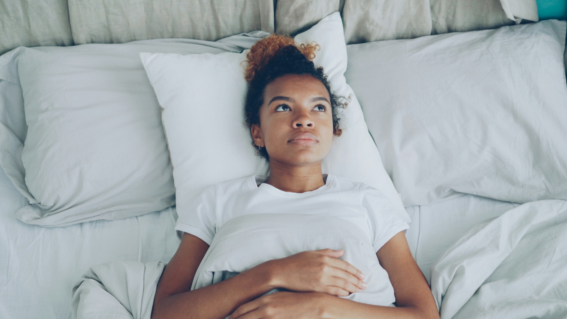 Young woman lying in bed with pillow.