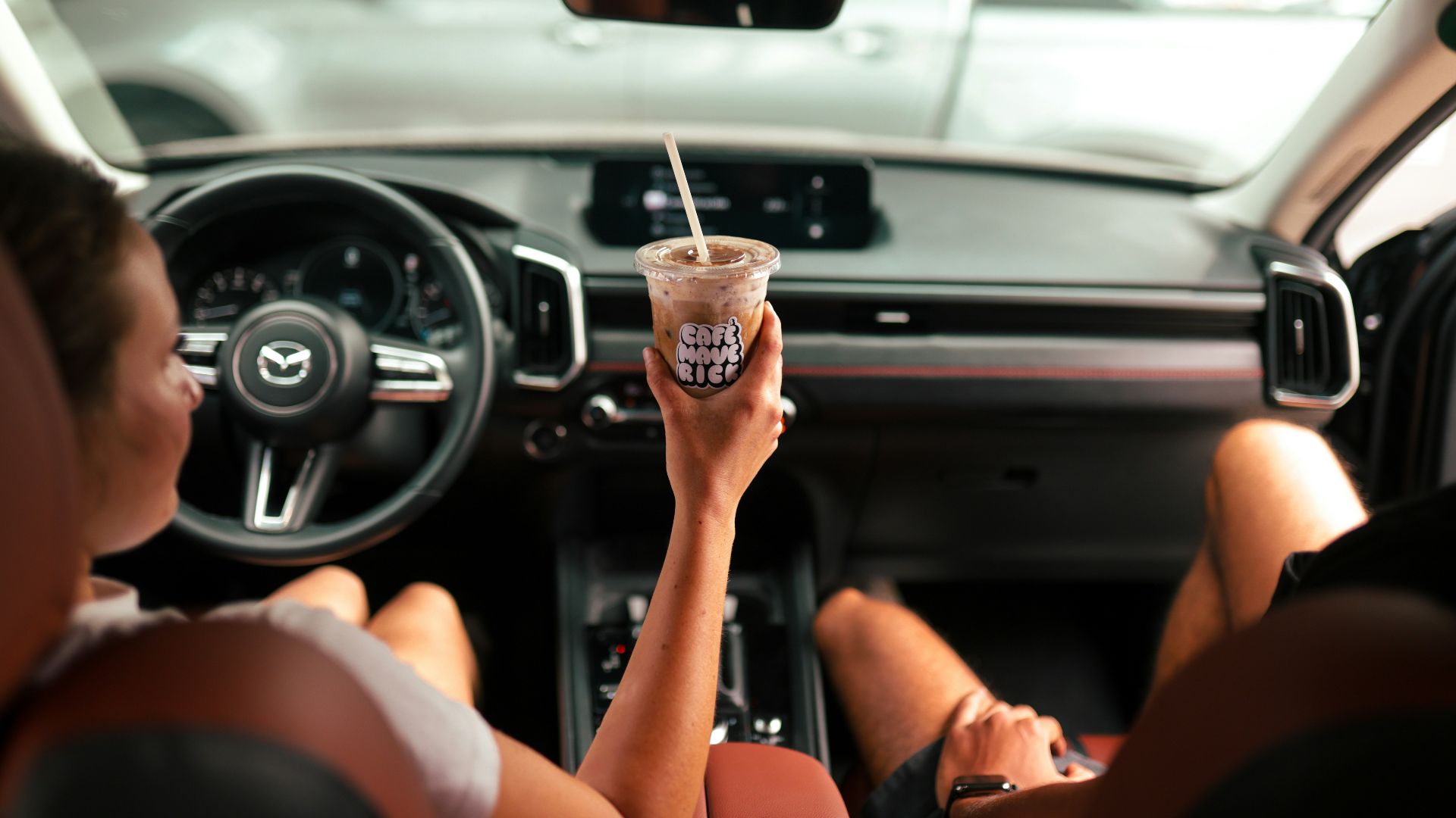 Woman holding coffee drink inside car