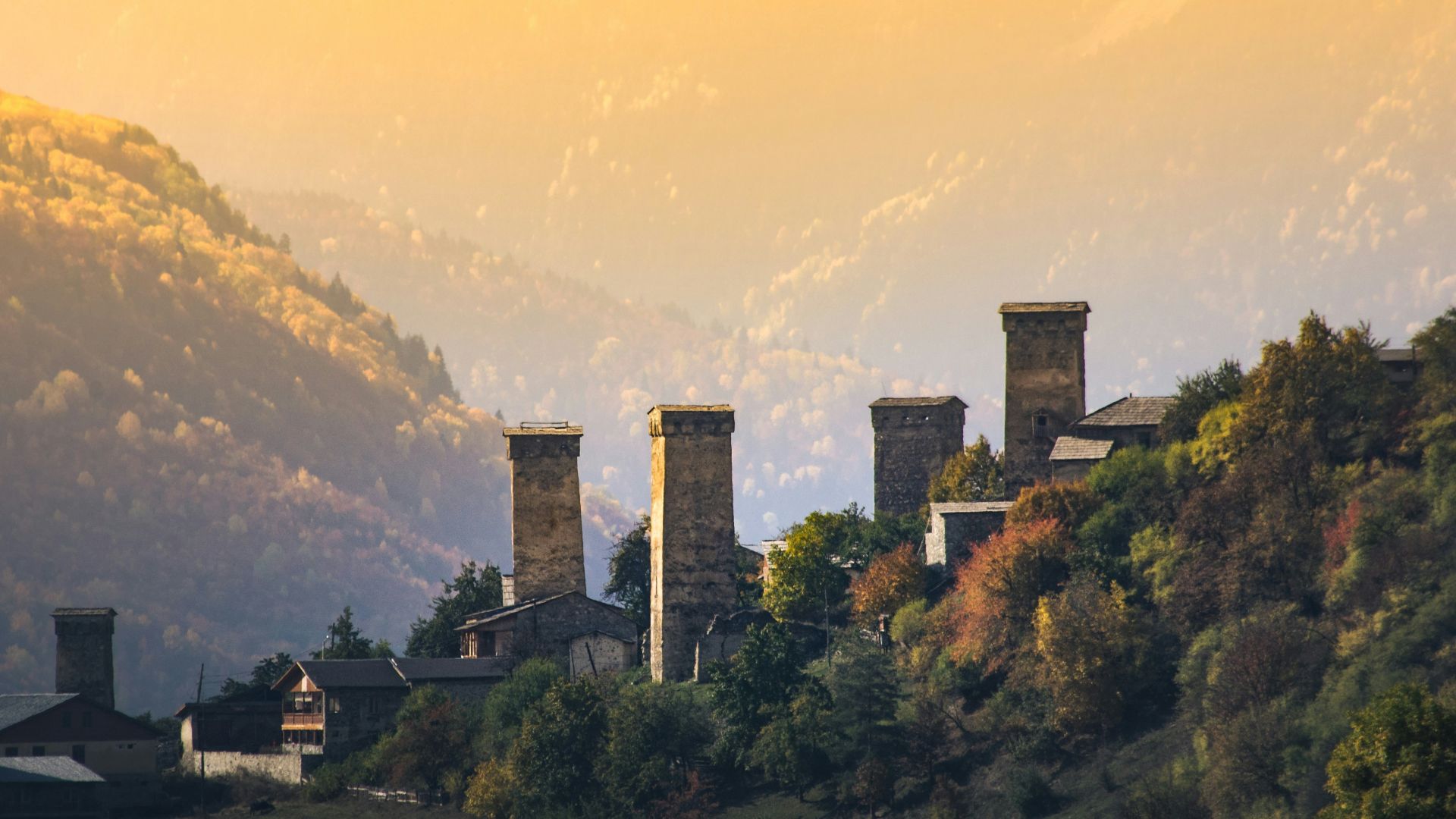 a row of towers on a hillside with a mountain in the background