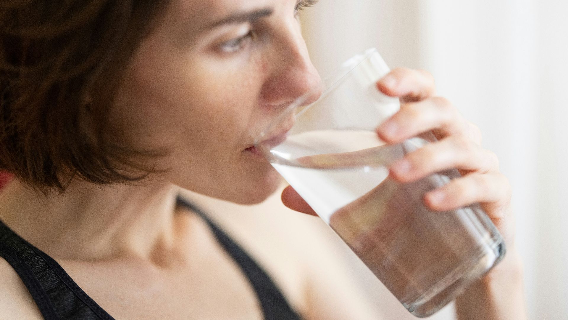 woman in black tank top drinking water